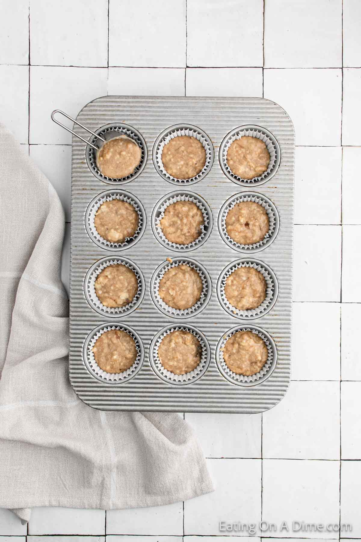 Muffin batter being divided in a muffin pan