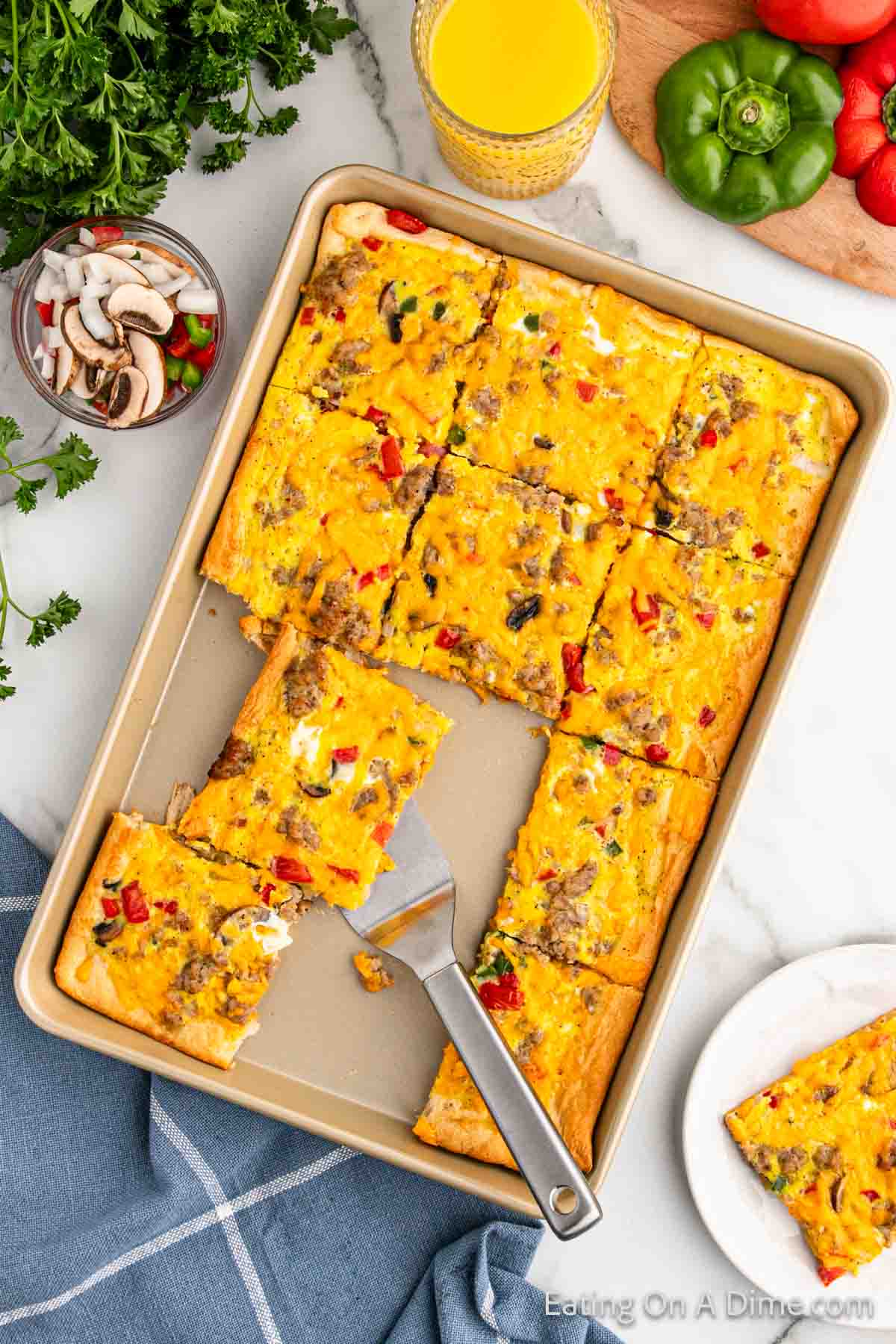 Crescent Roll Breakfast Pizza sliced on a baking sheet with several pieces mixing and one slice on a spatula