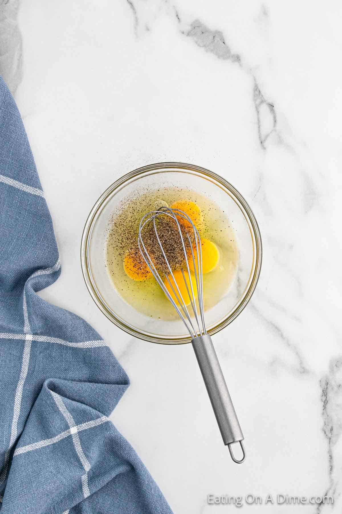 Whisking cracked eggs in a bowl with seasoning 