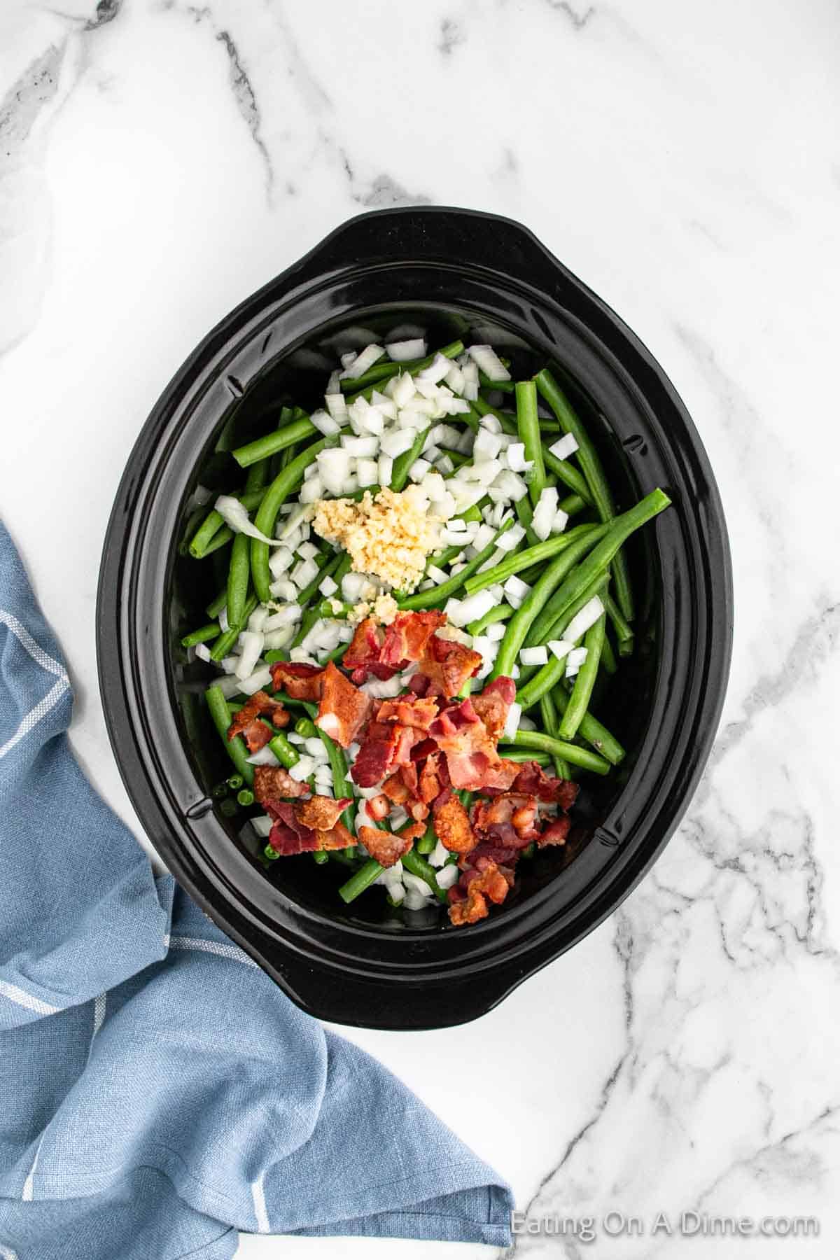 Fresh green beans in the slow cooker topped with bacon, onions, and garlic