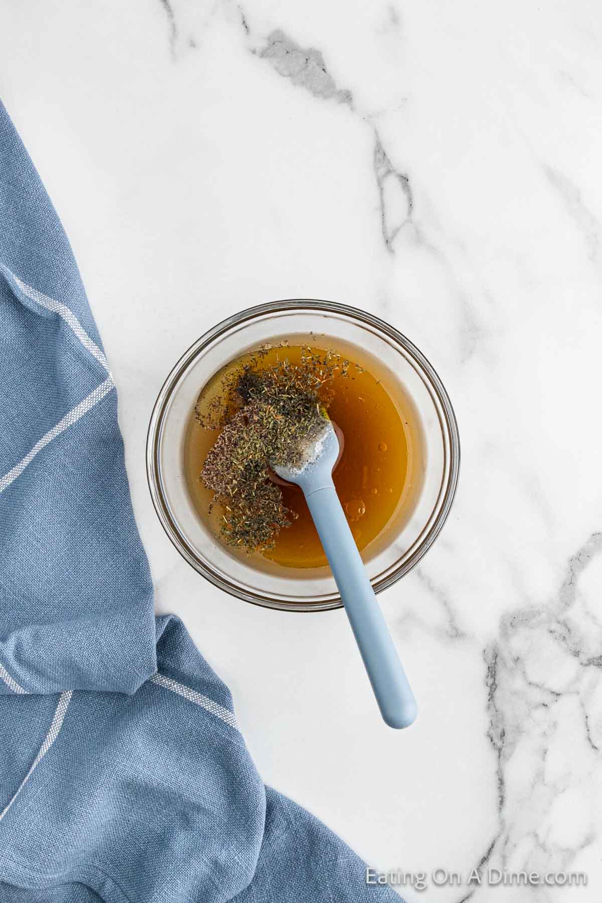 Combining broth, olive oil, salt, pepper and thyme in a bowl with a spatula