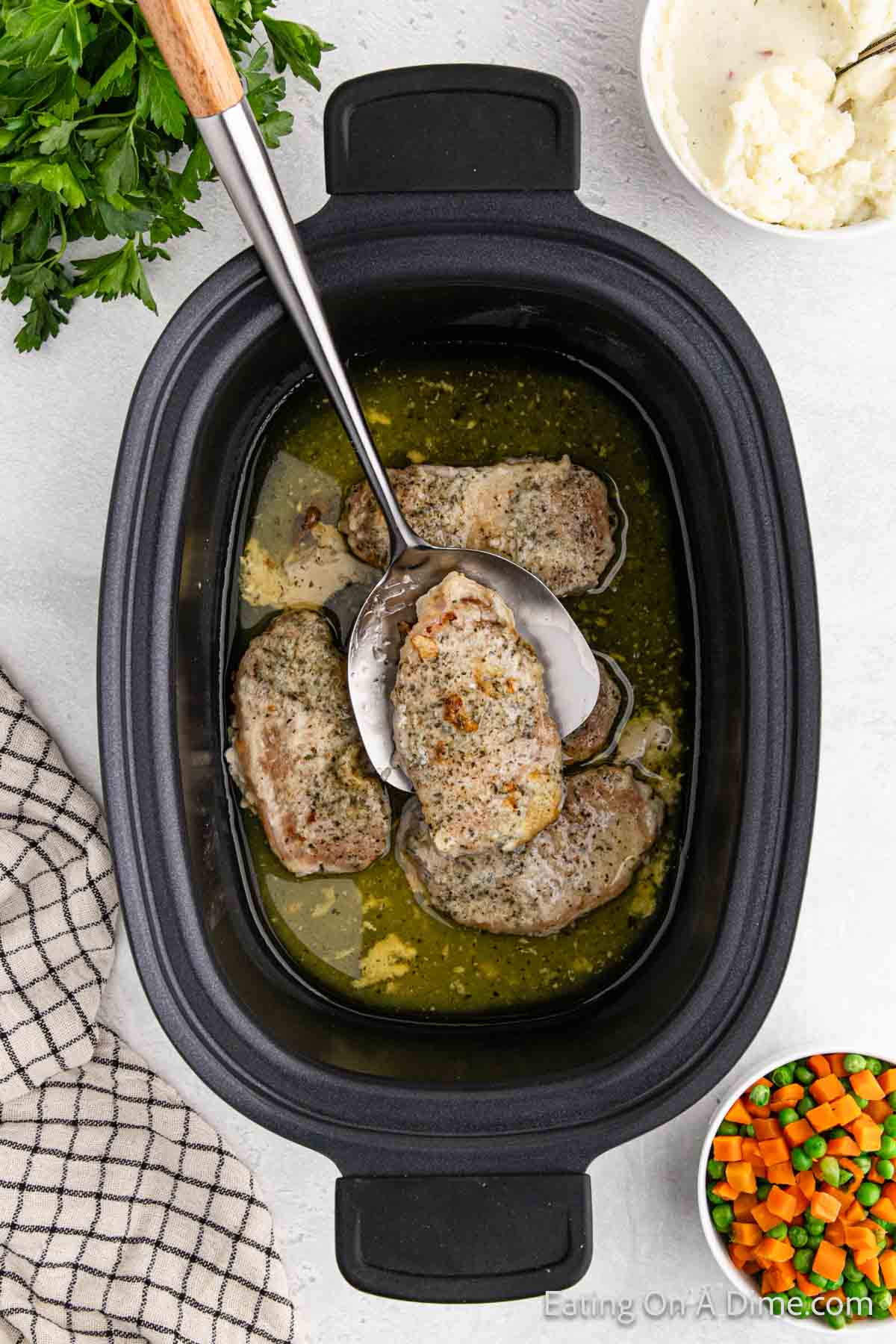 Cooked pork chops in a slow cooker with a buttery sauce