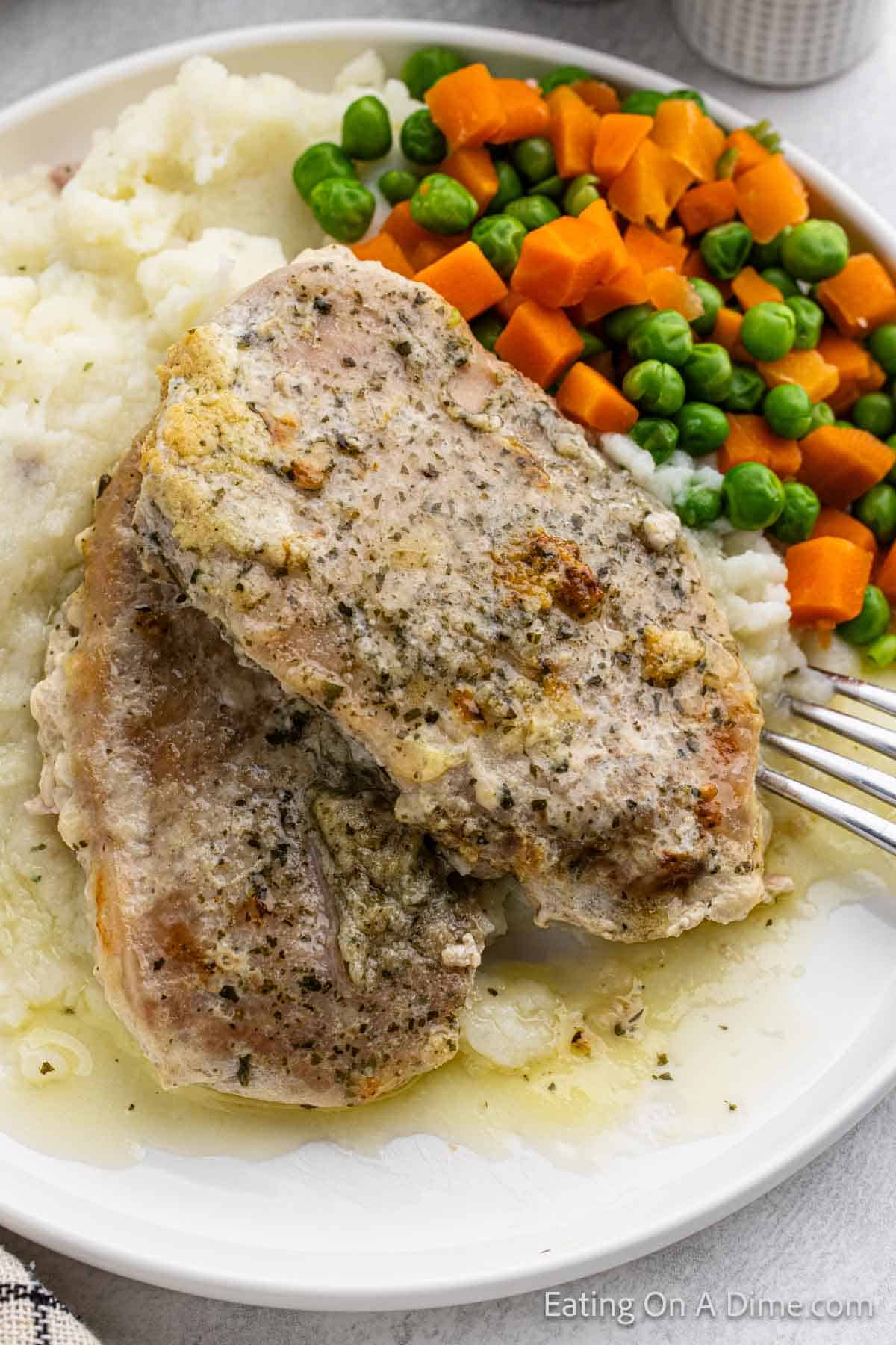Ranch Pork Chops on a plate with mashed potatoes and a peas and carrot mixture