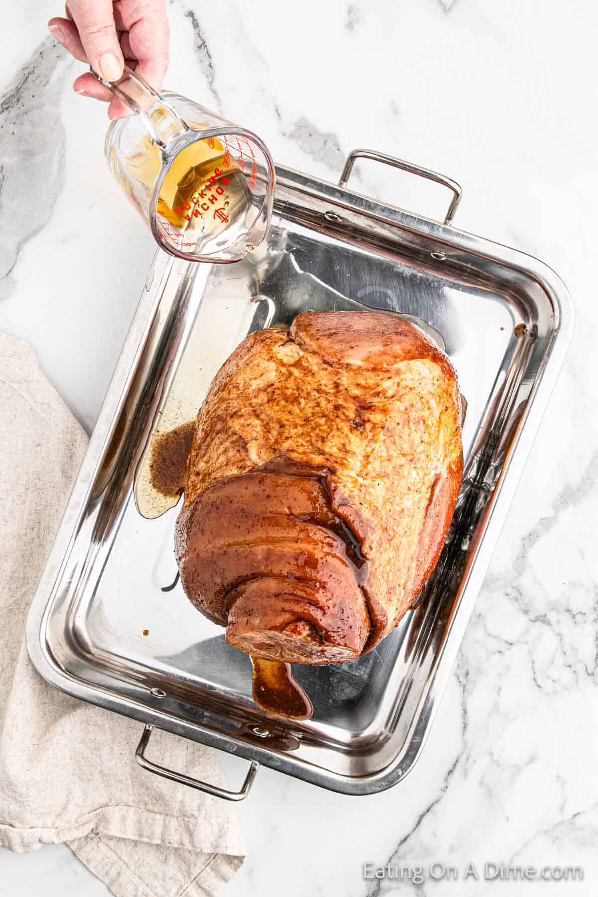 Pouring apple juice over ham in a roasting pan