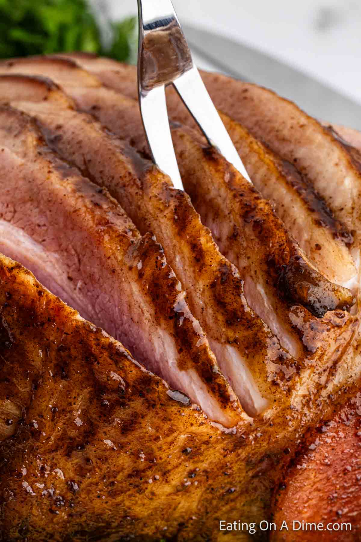 Close up image of slice ham with a large fork