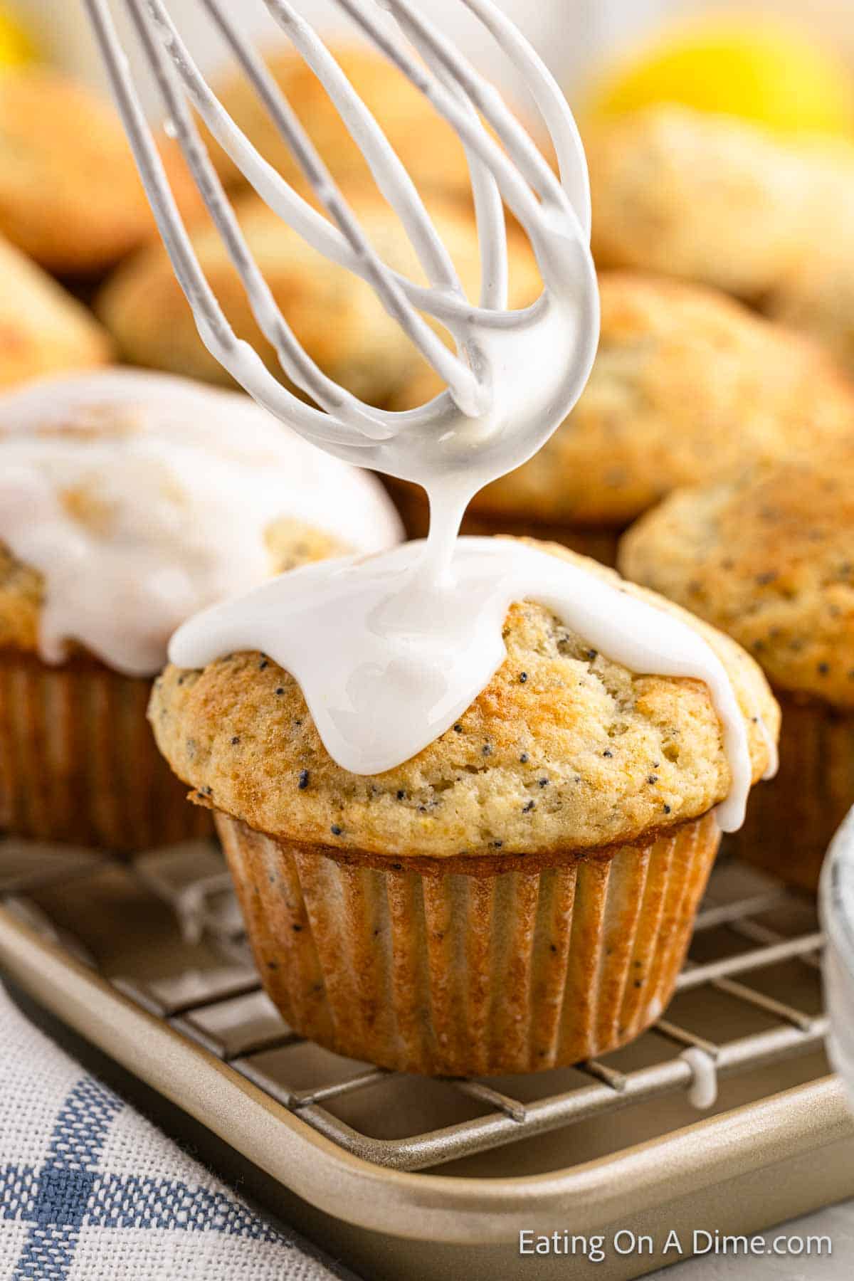 Glaze being drizzled over the topped of a baked muffin