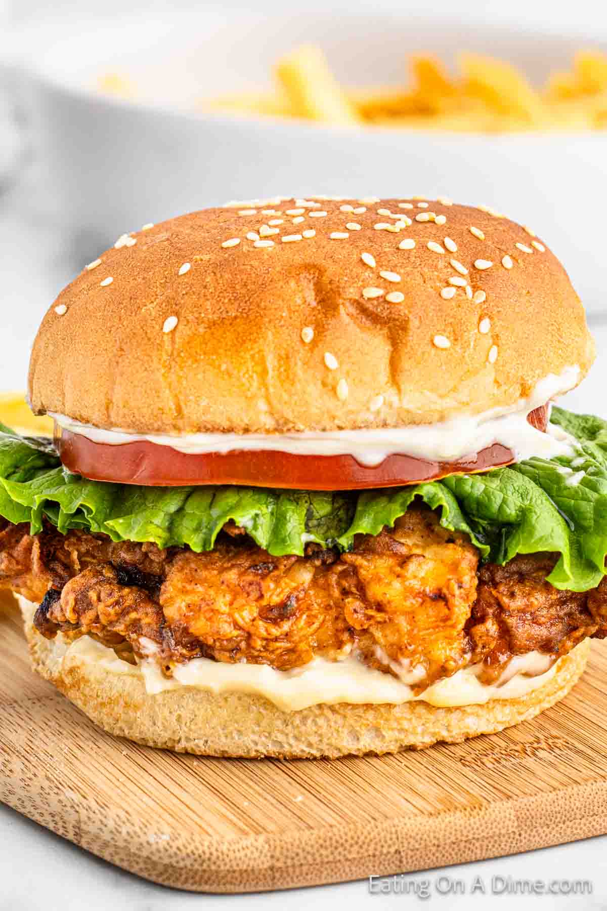 Crispy Chicken Sandwich topped with mayo, slice tomato, and lettuce with a sesame bun