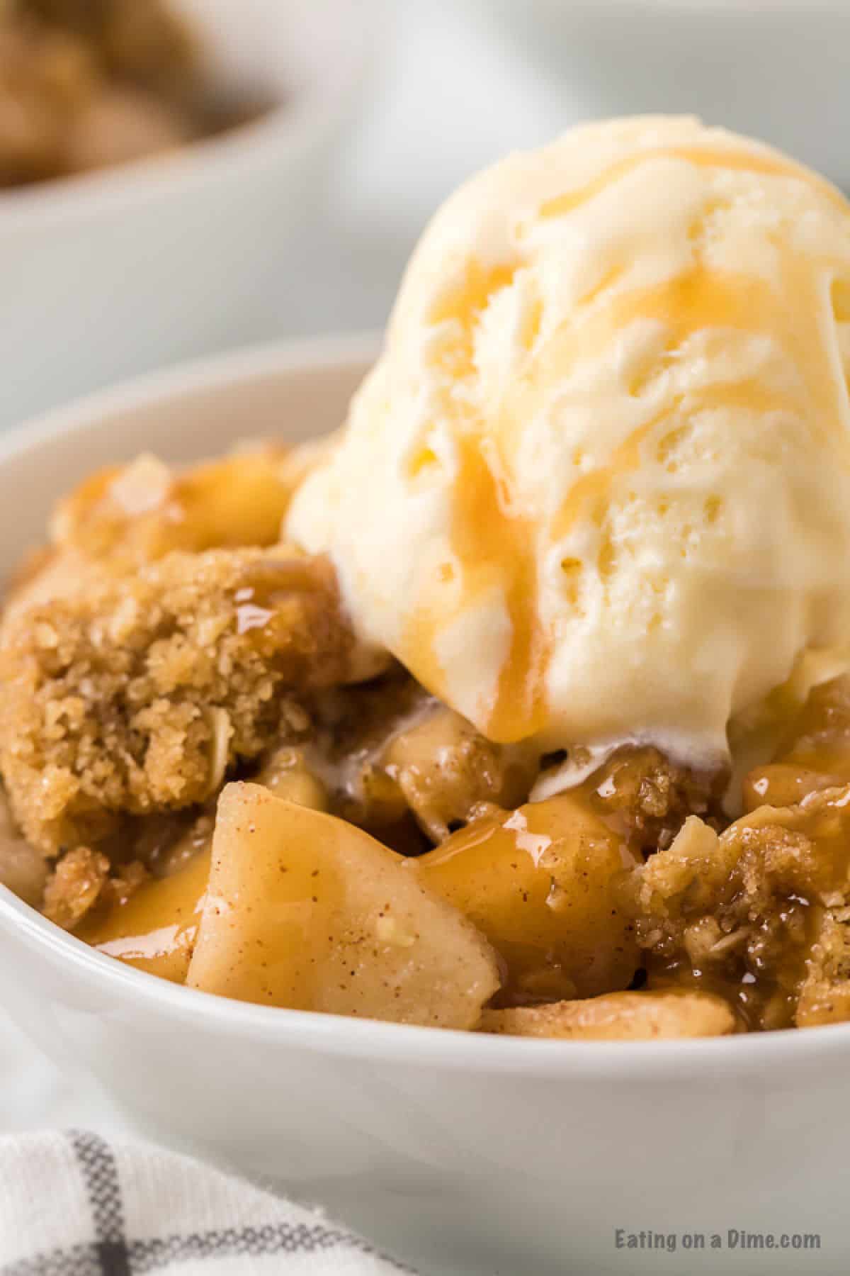 bowl of apple crisp with ice cream and caramel sauce