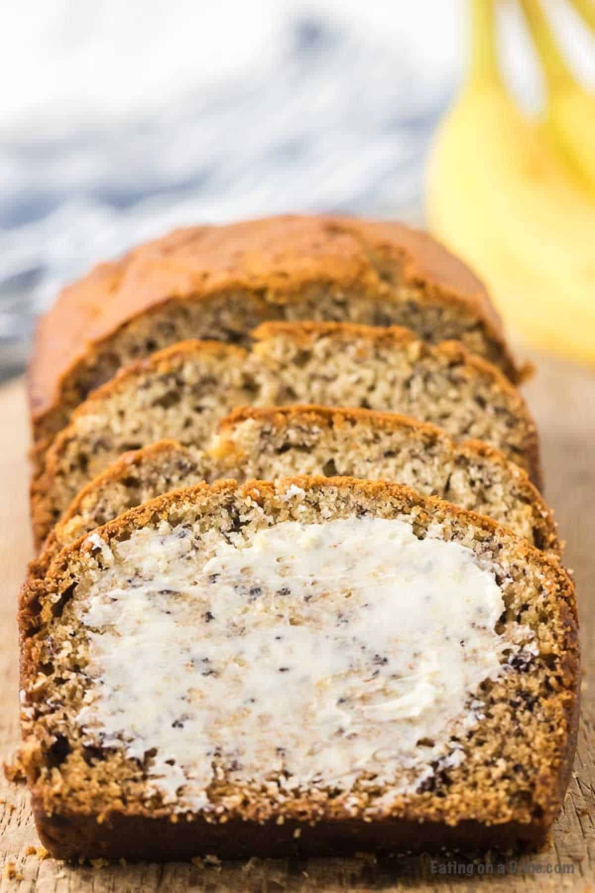 Banana bread sliced with the first topped with butter