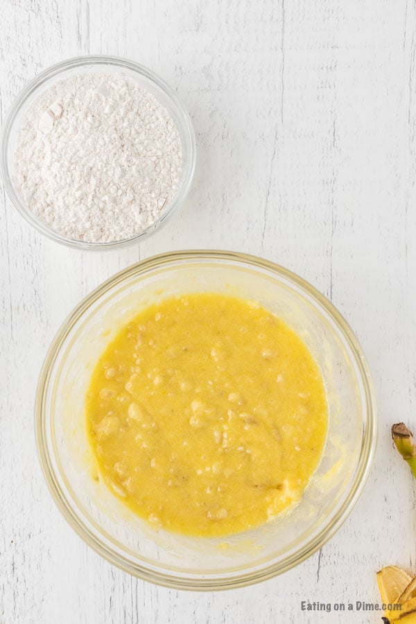 Mixing the butter, eggs, vanilla, sugar, salt in a bowl with a bowl of flour on the side