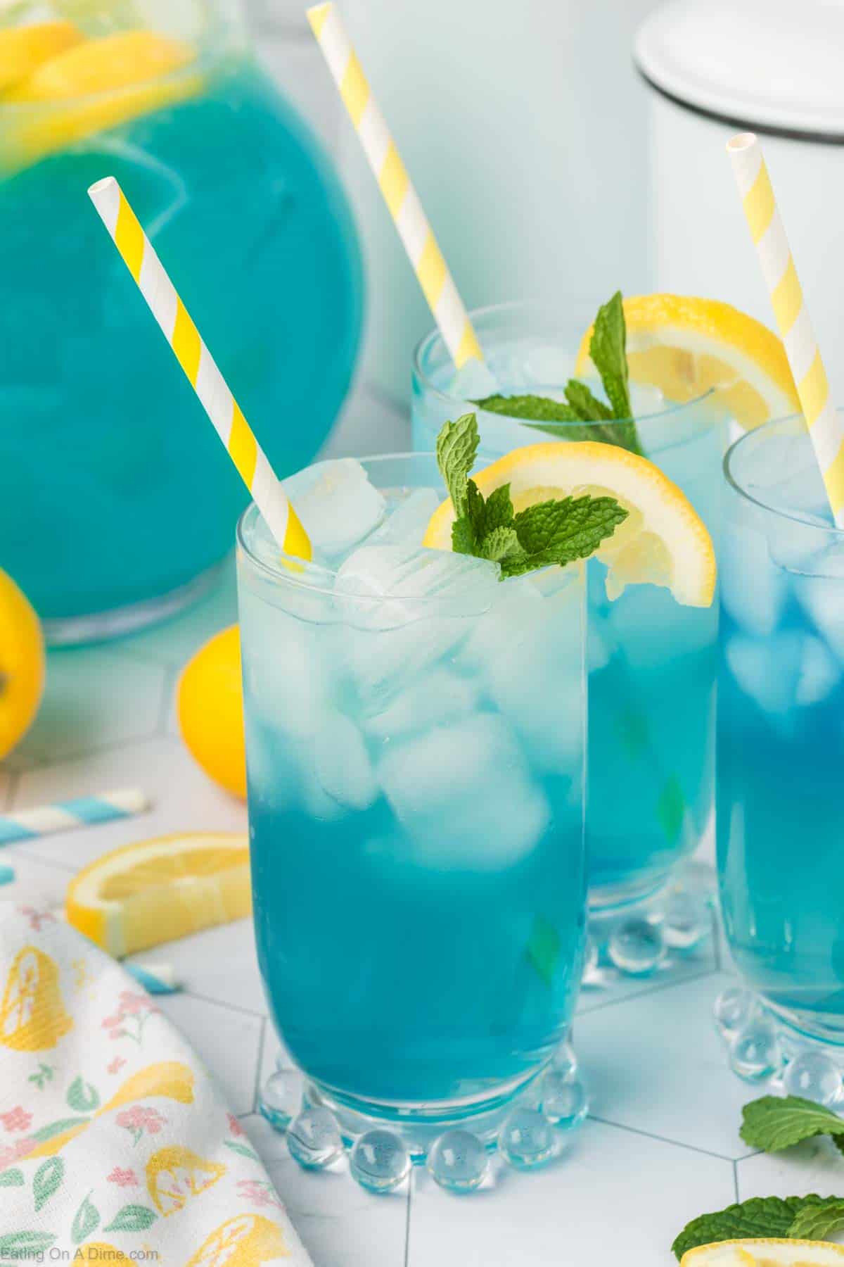 Blue lemonade in a glass topped with slice lemons and fresh mint