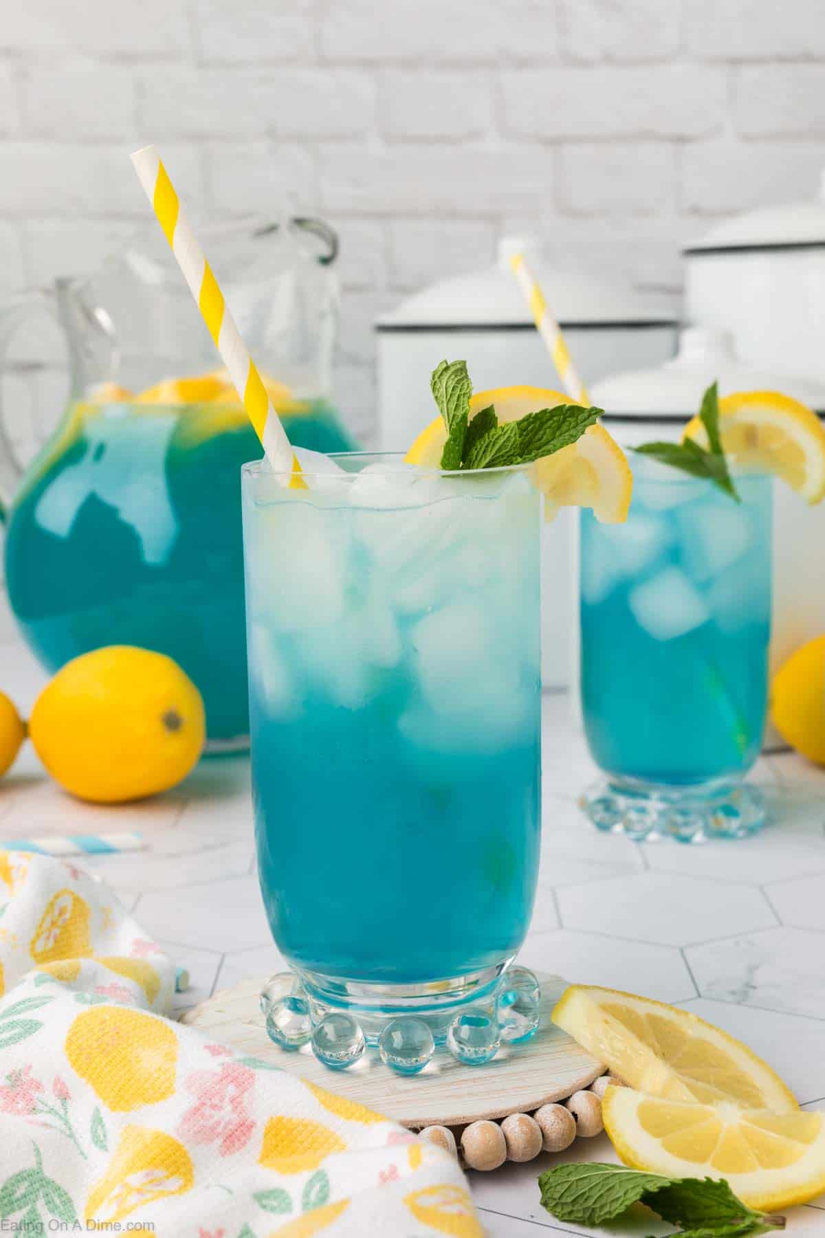 Blue lemonade in a glass topped with slice lemons and fresh mint