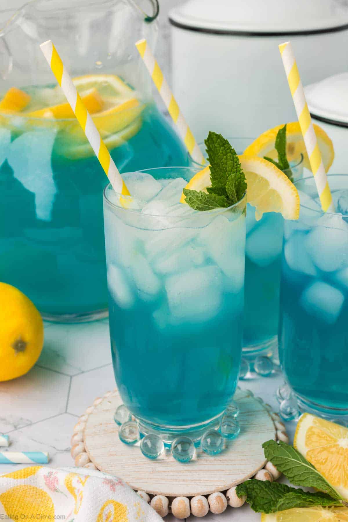 Blue lemonade in a glass topped with slice lemons and fresh mint