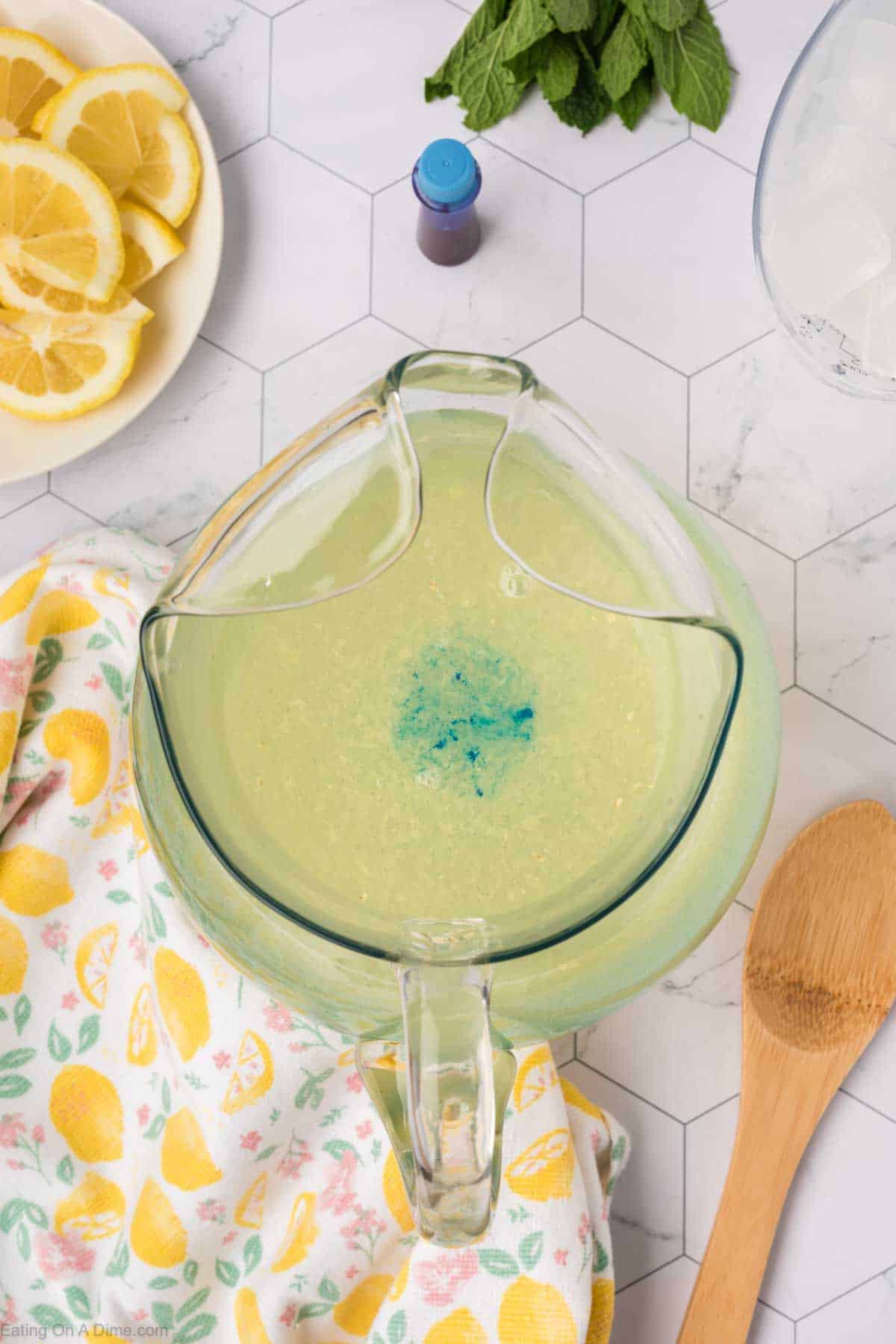 Dropping blue food coloring into the pitcher of lemonade