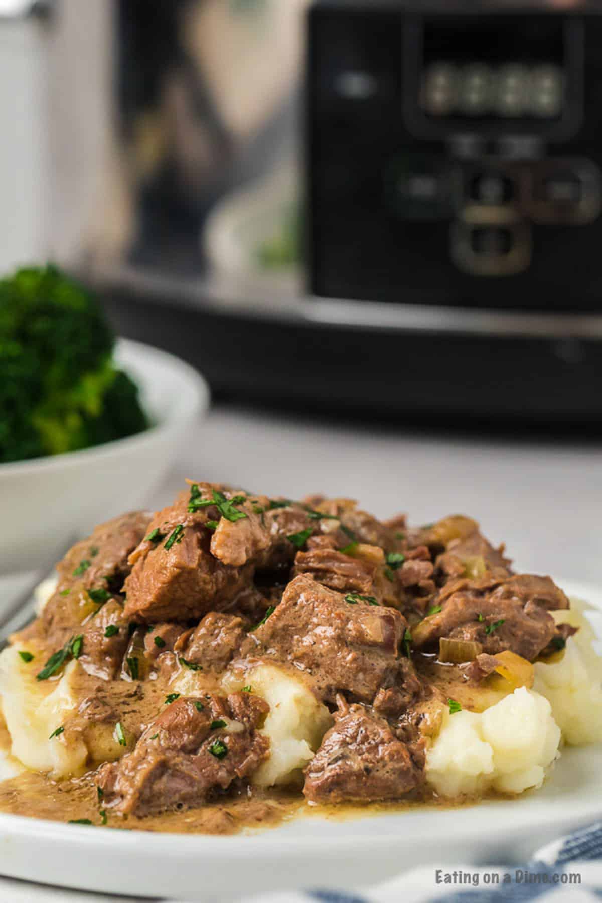 If you need a simple recipe that everyone is sure to love, try Crockpot Beef Tips Recipe. The beef is so tender and the gravy is amazing. Beef Tips and gravy over mashed potatoes on a plate
