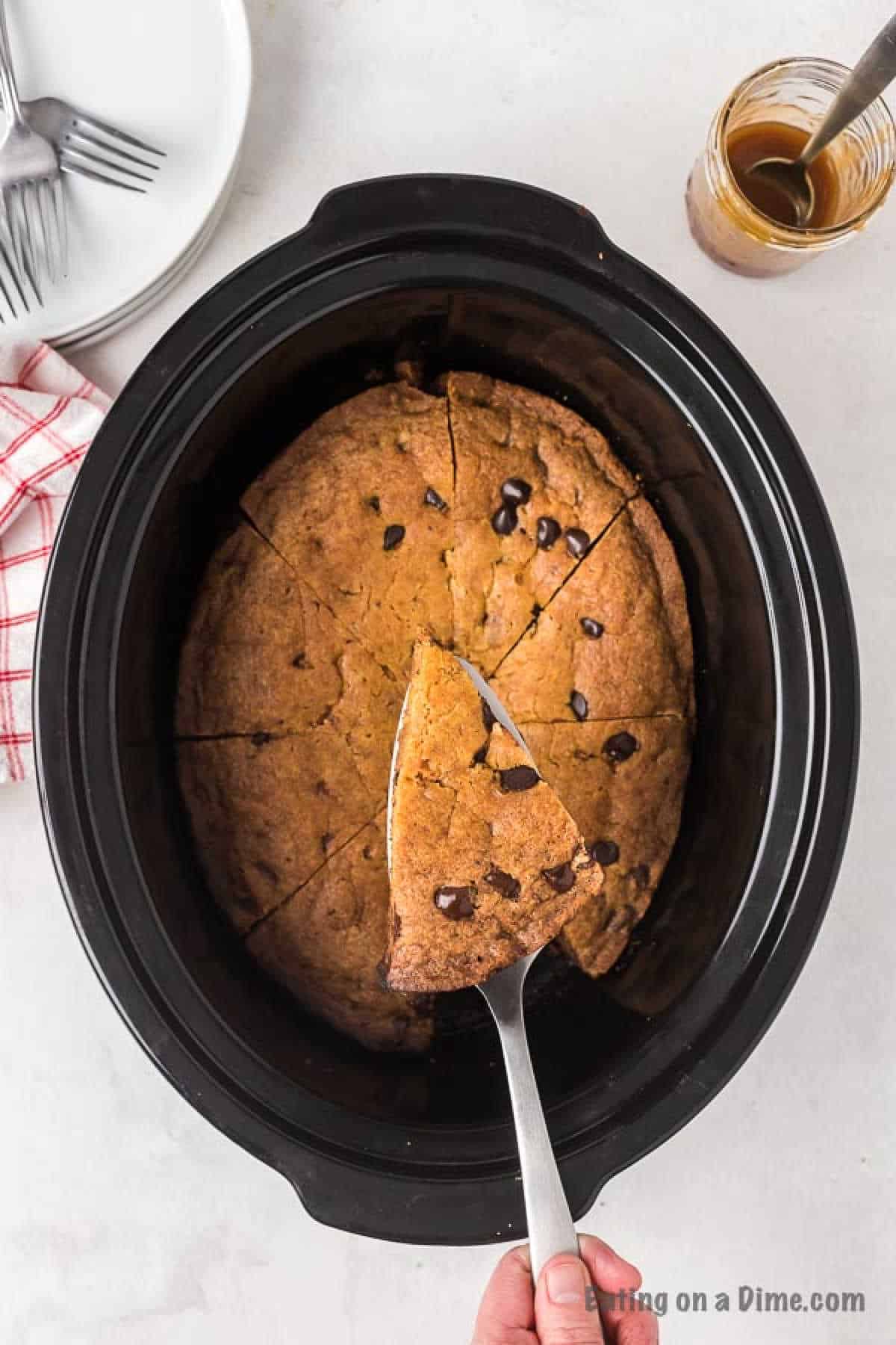 Chocolate chip cookie in the slow cooker with a slice of cookie on a spatula