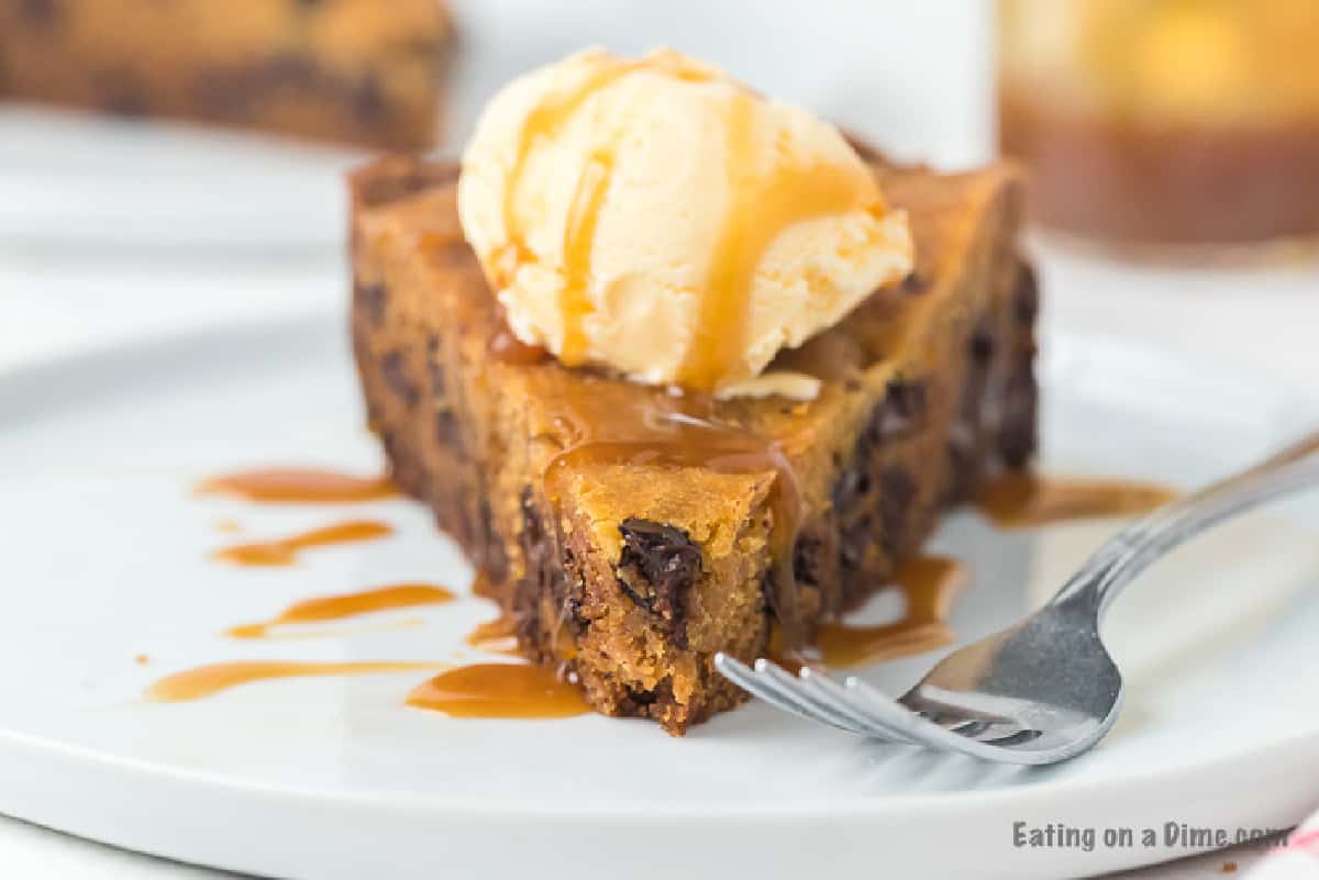 Slice of Chocolate Chip Cookie on a plate topped with caramel syrup and ice cream