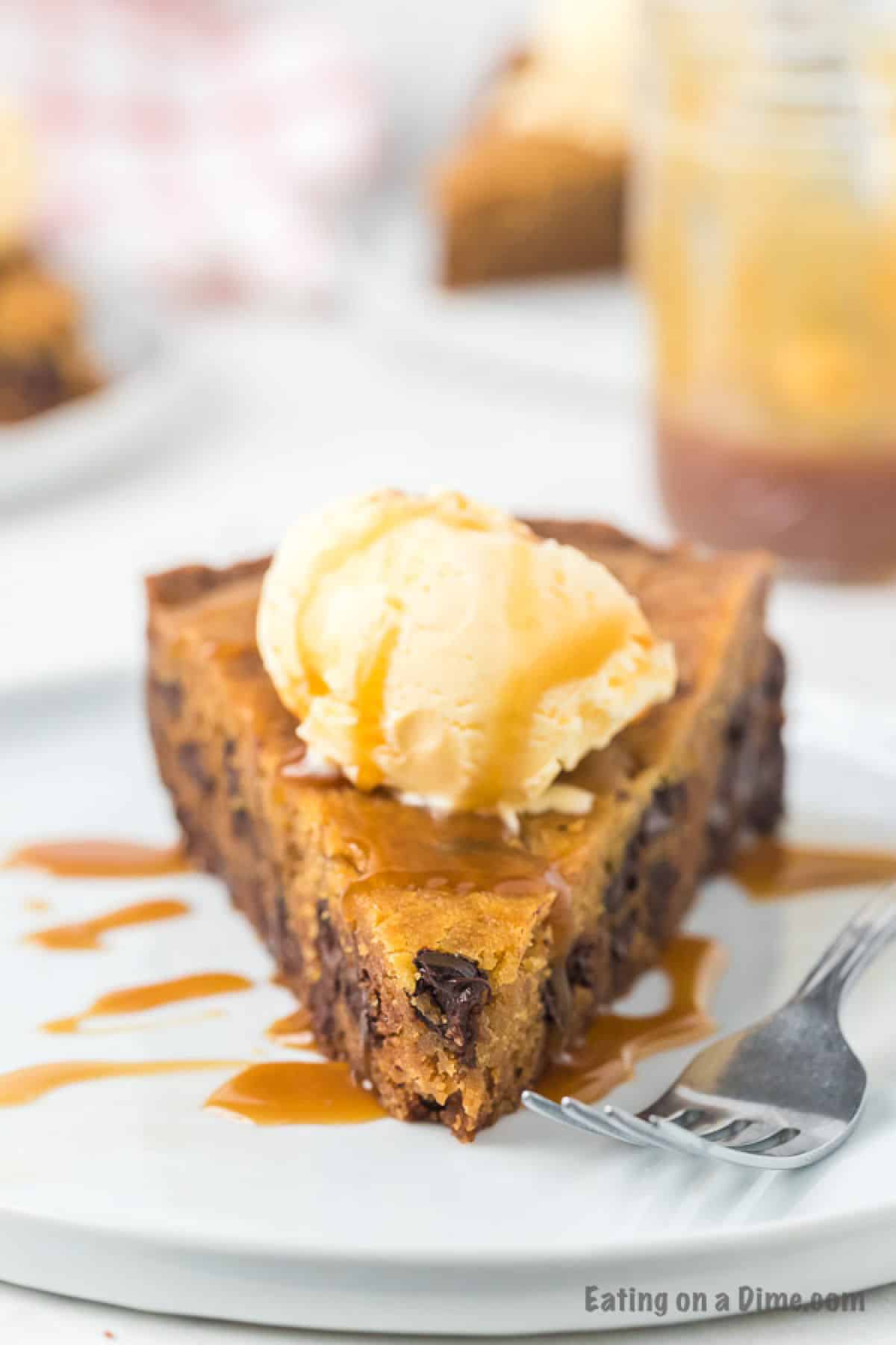 Slice of chocolate chip cookie drizzled with caramel sauce and topped with vanilla ice cream