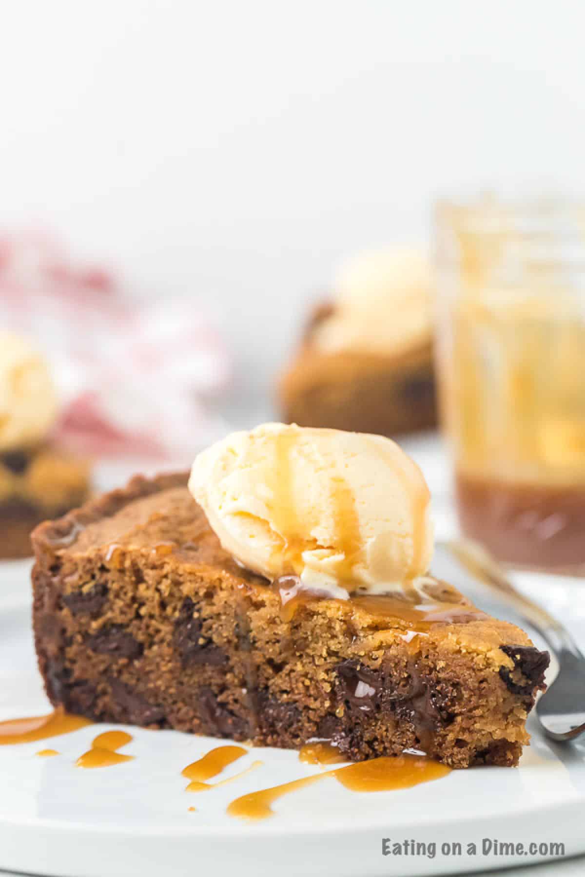 Slice of Chocolate Chip Cookie on a plate topped with caramel sauce and a scoop of ice cream