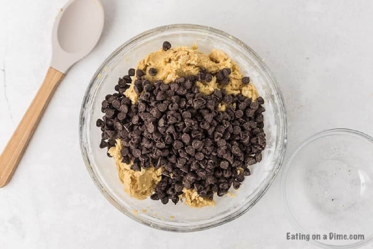 Topping the cookie dough batter with chocolate chips in a bowl