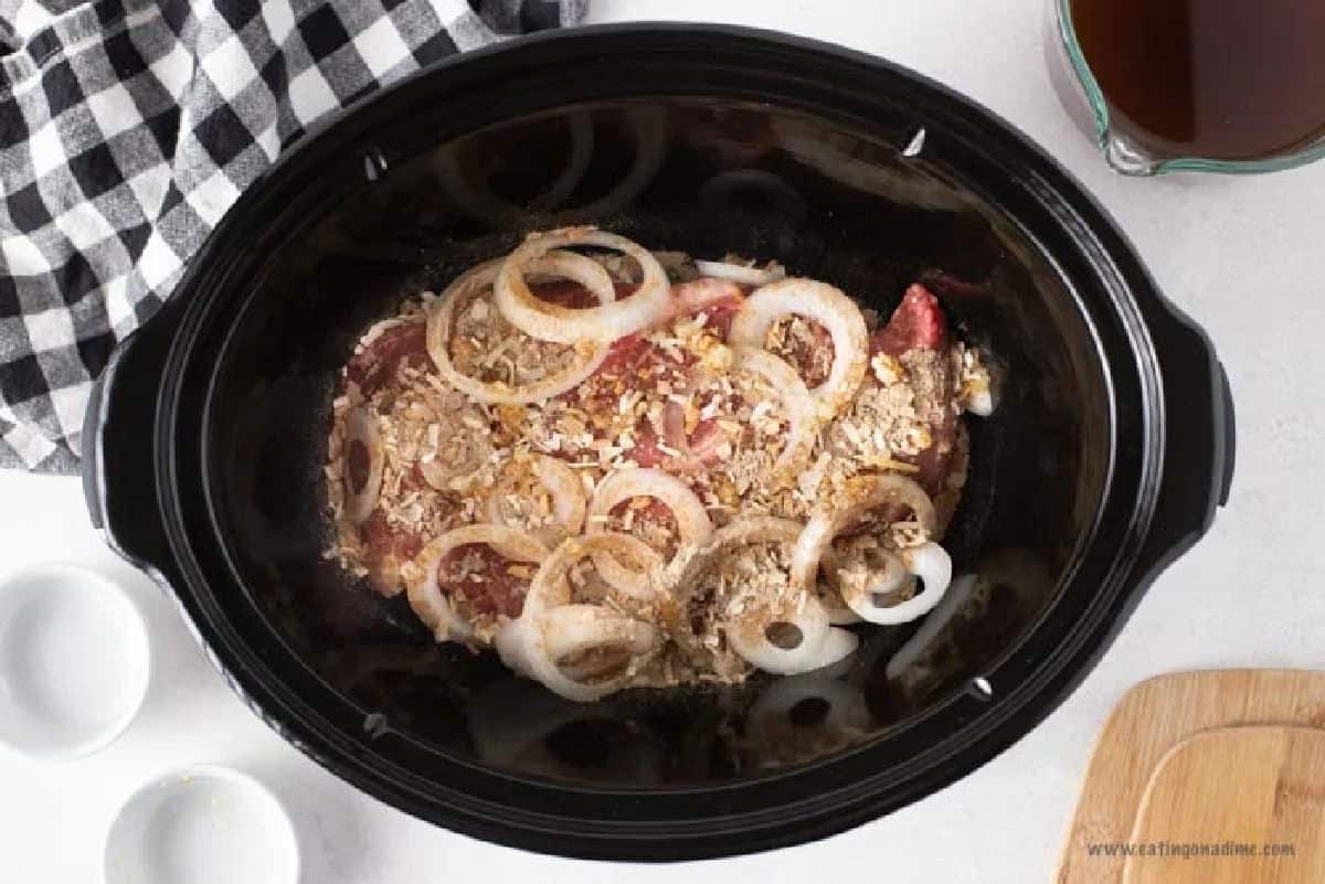 Placing the seasoning and onions with the roast in the slow cooker