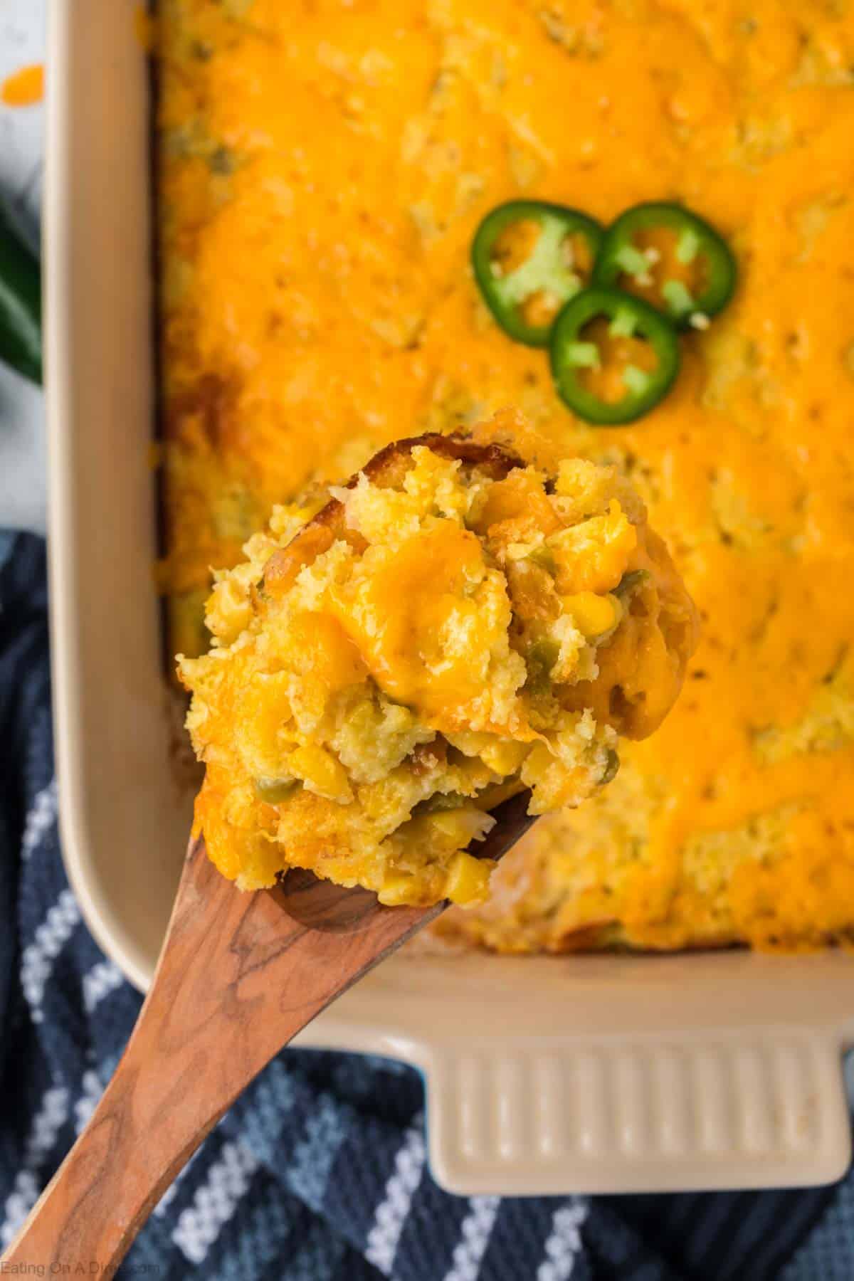 Jalapeno Corn Casserole in a baking dish with a serving on a wooden spoon