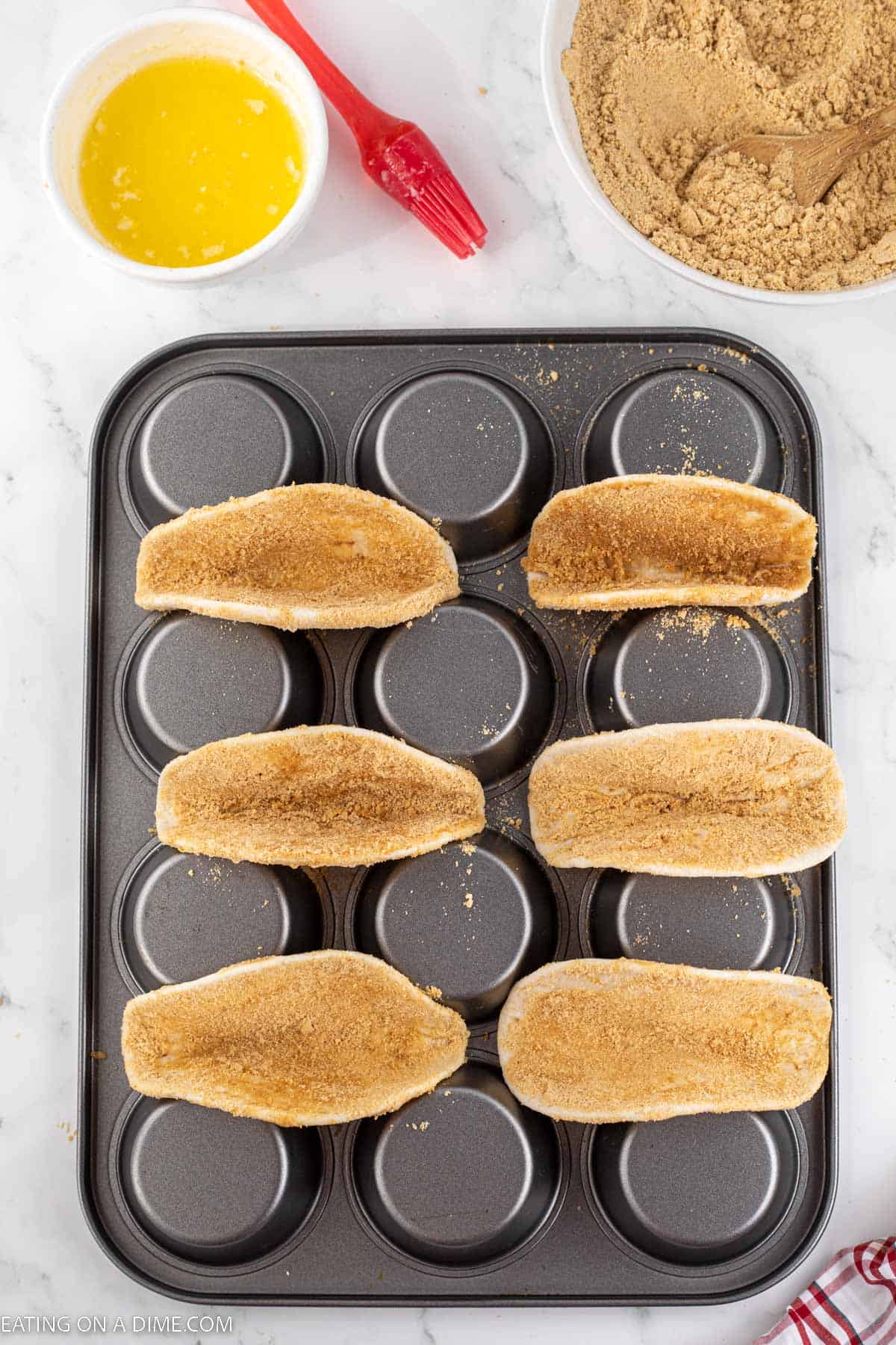Graham cracker covered flour tortillas are shaped into a taco shell and placed on the bottom of a muffin pan with a bowl of melted butter and graham cracker mixture on the side.