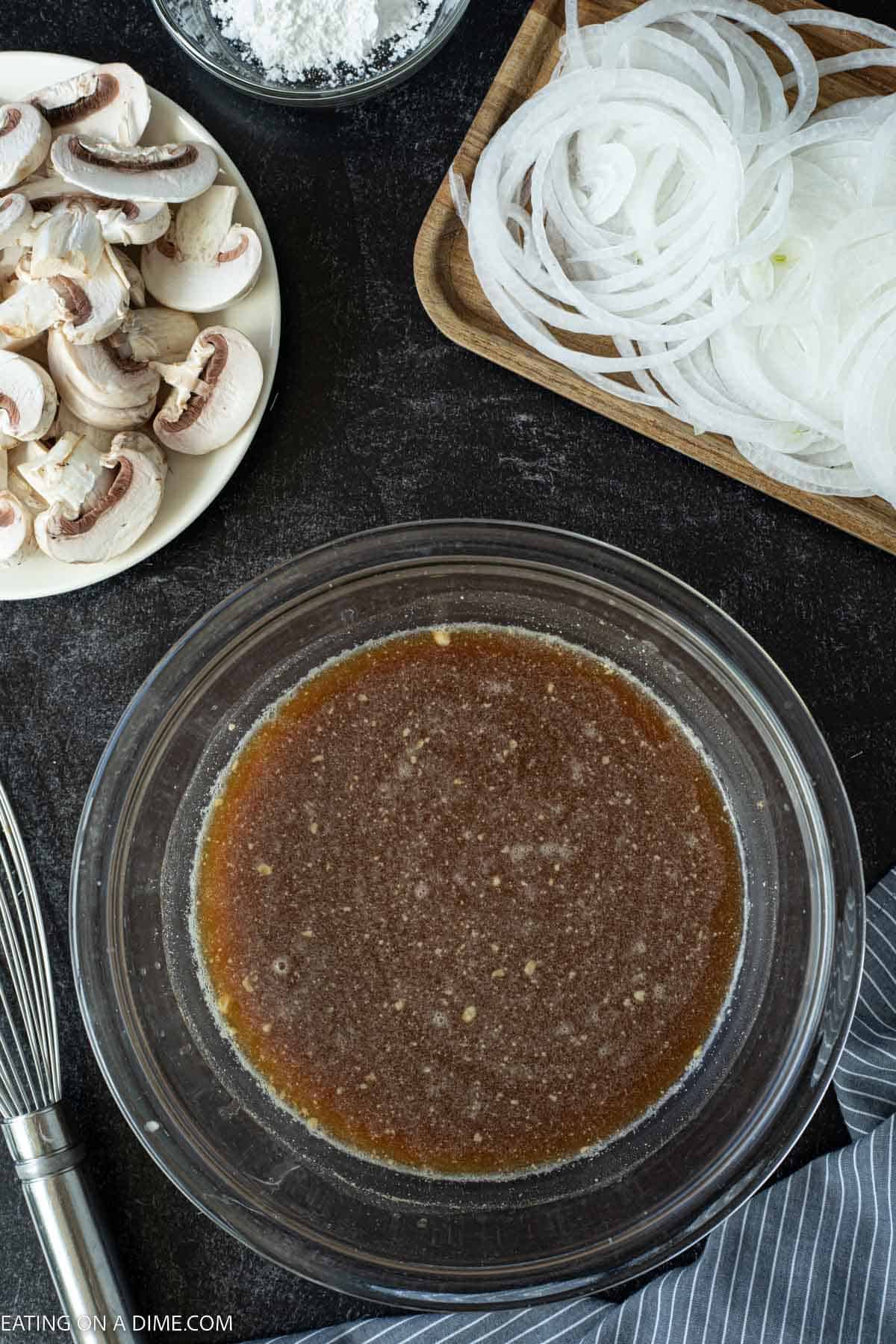 Mixing the gravy ingredients in a bowl with a side of slice mushrooms and onions in a bowl