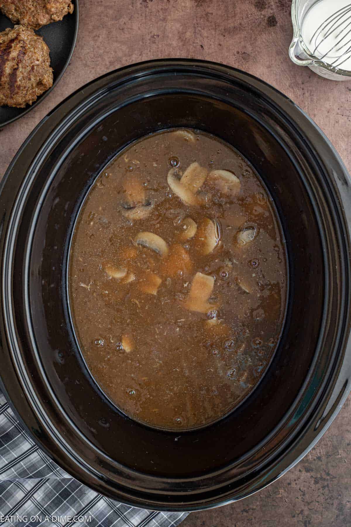 Pouring mixture over beef patties in the slow cooker