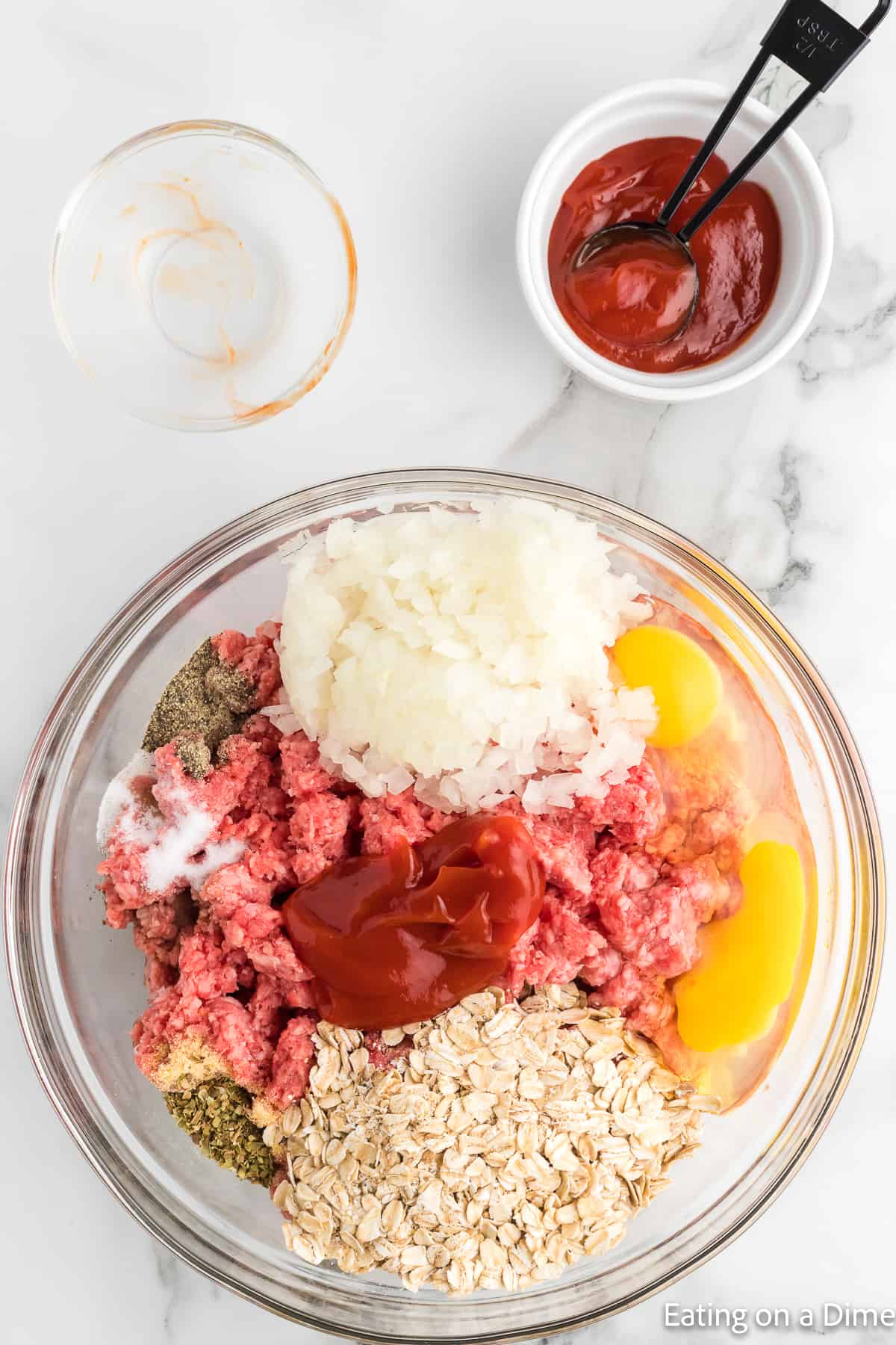 Combining the ground beef with, otas, eggs, onions, ketchup and seasoning in a bowl
