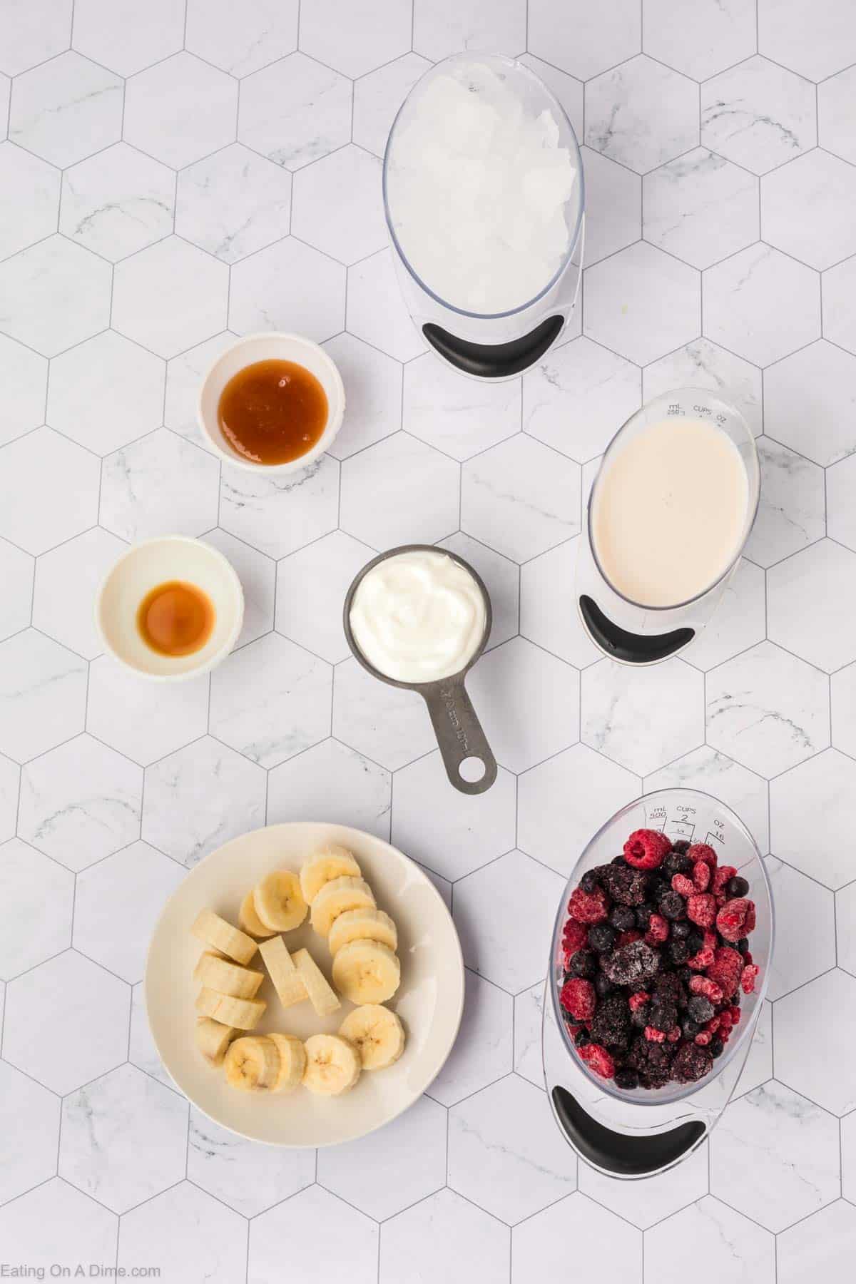 Mixed berries smoothie ingredients - ice, honey, vanilla, milk, yogurt, slice bananas, and frozen mixed berries