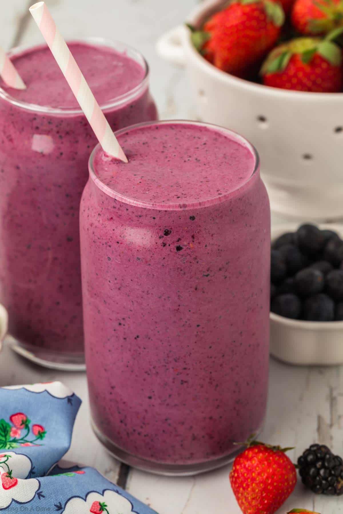 Mixed berry smoothie in a clear glass with a straw
