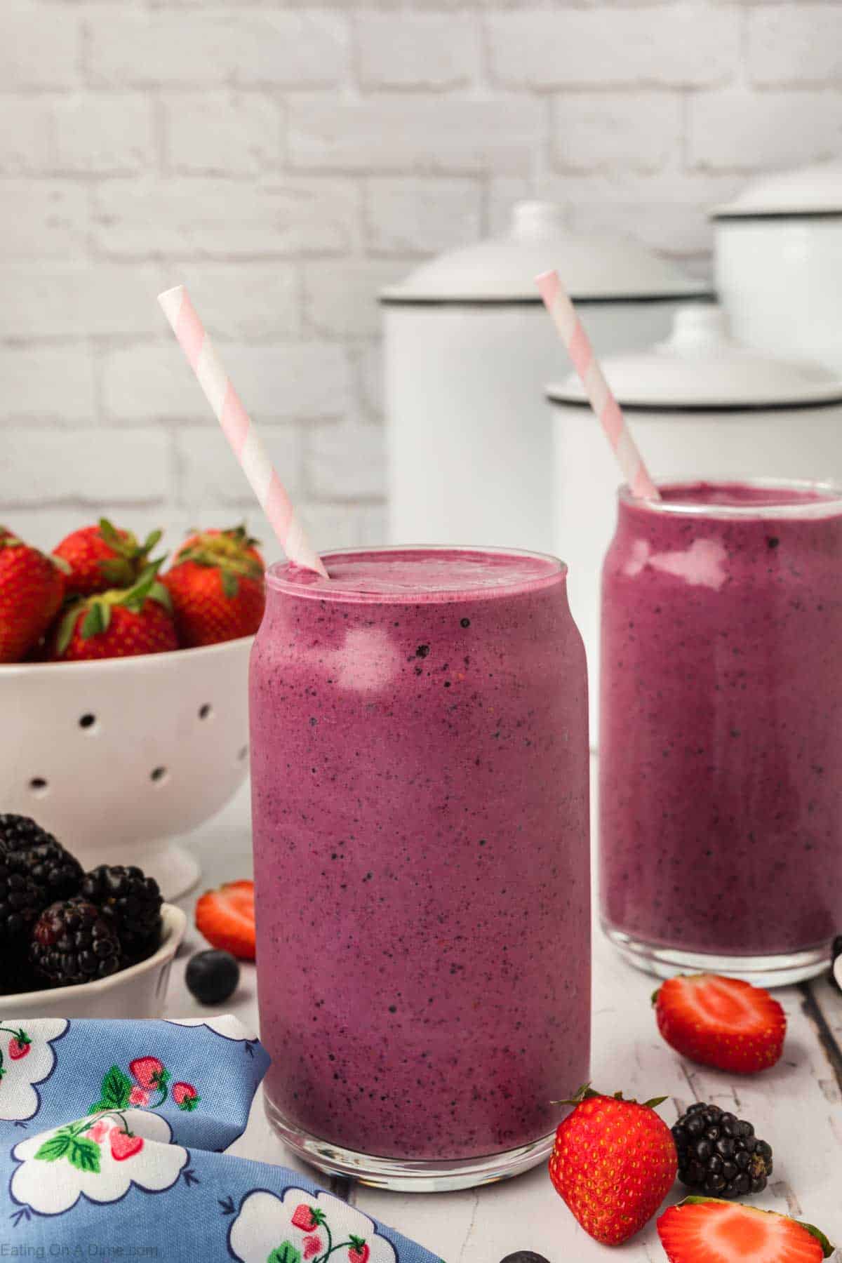 Mixed berries smoothie in a clear glass with a straw