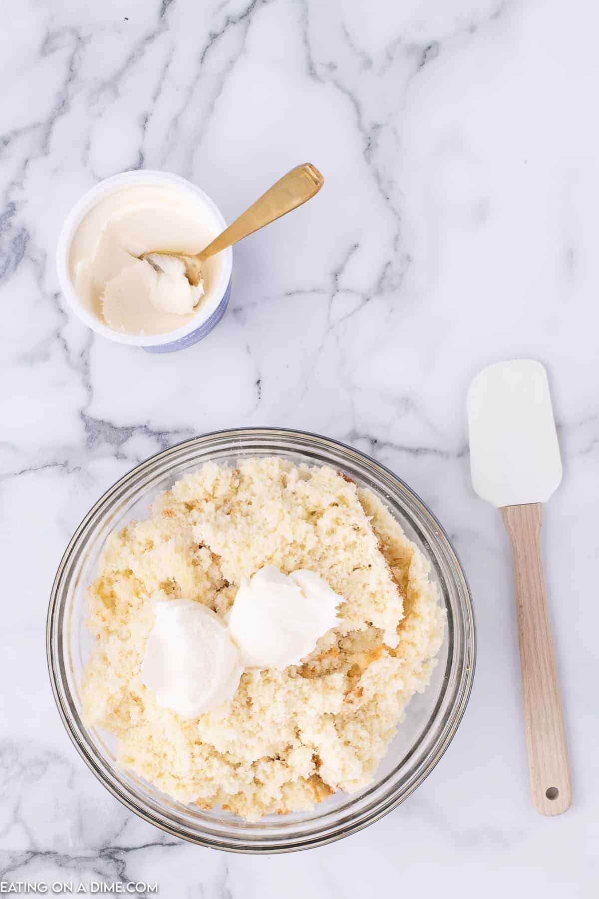 Mixing the frosting into the crumbled cake in a bowl