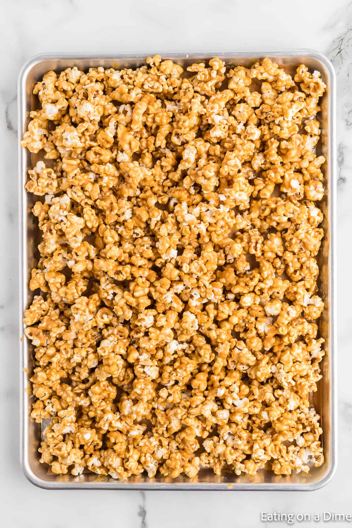 Caramel popcorn spread out on the baking sheet