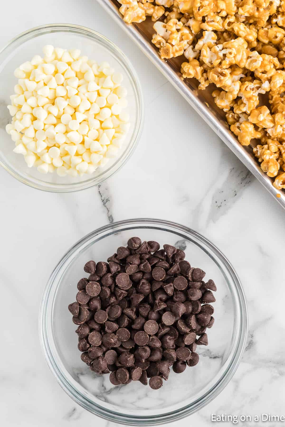 Bowl of chocolate chips with a baking sheet of popcorn on the side