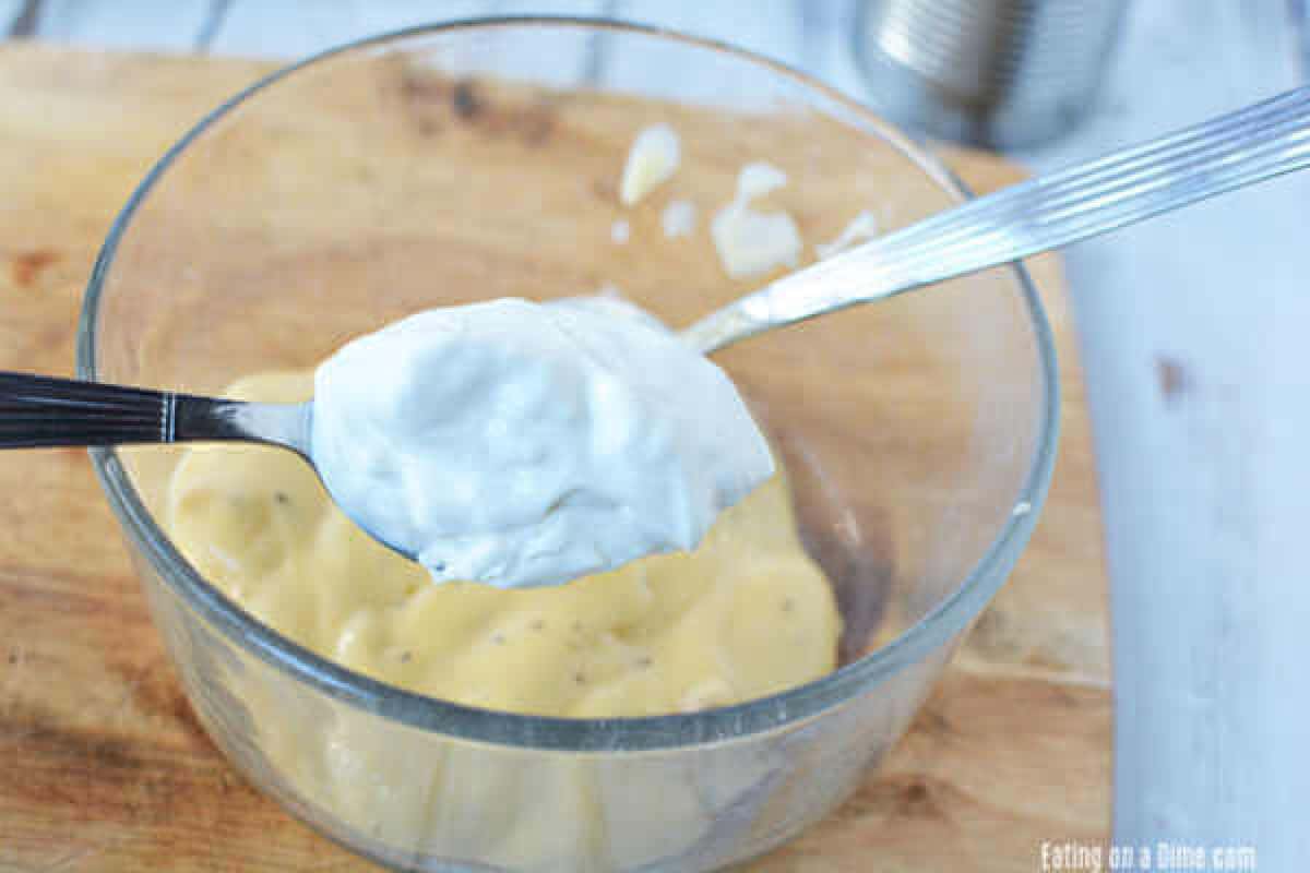 Combining cream of chicken soup with sour cream and milk in a bowl with a spoon