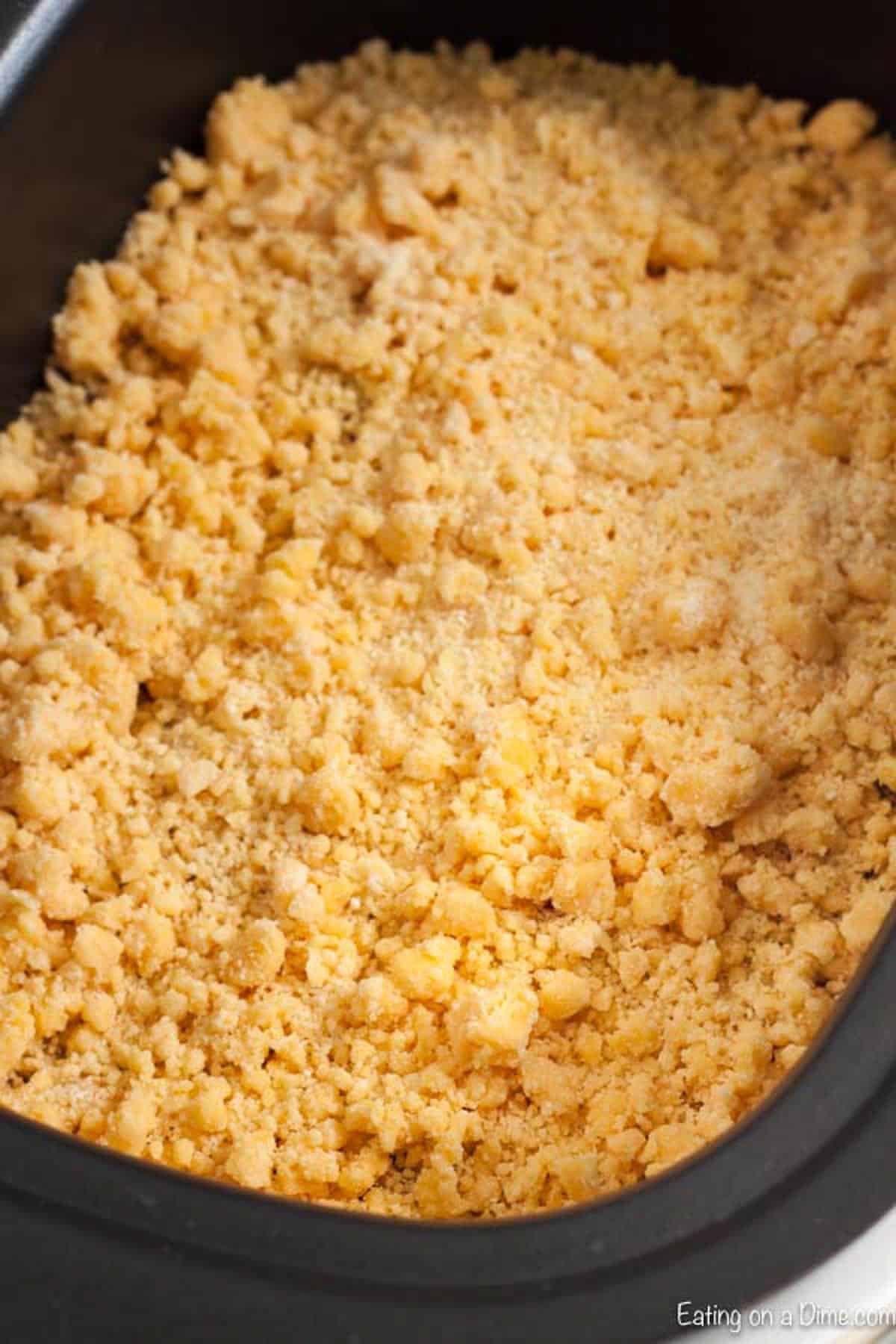 Topping the cherry pie filling in the crock pot with the cake mix crumble