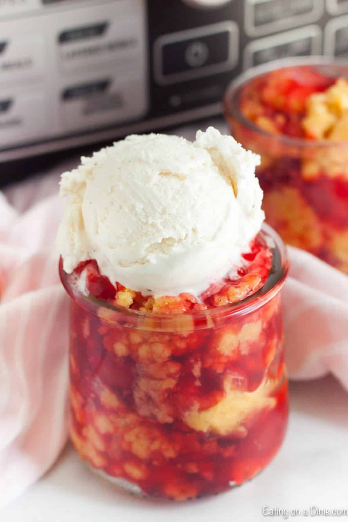 Crock Pot Cherry Dump Cake Recipe is so easy with only 3 ingredients. Cherries and the best topping come together for a recipe that will melt in your mouth. Cherry Dump Cake in a jar topped with vanilla ice cream