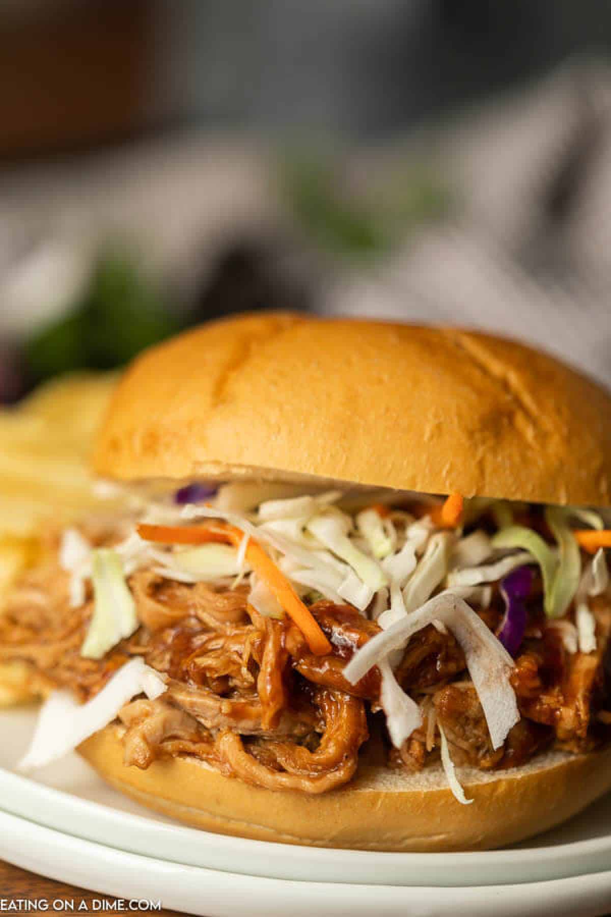 Pulled pork sandwich topped with slaw on a plate