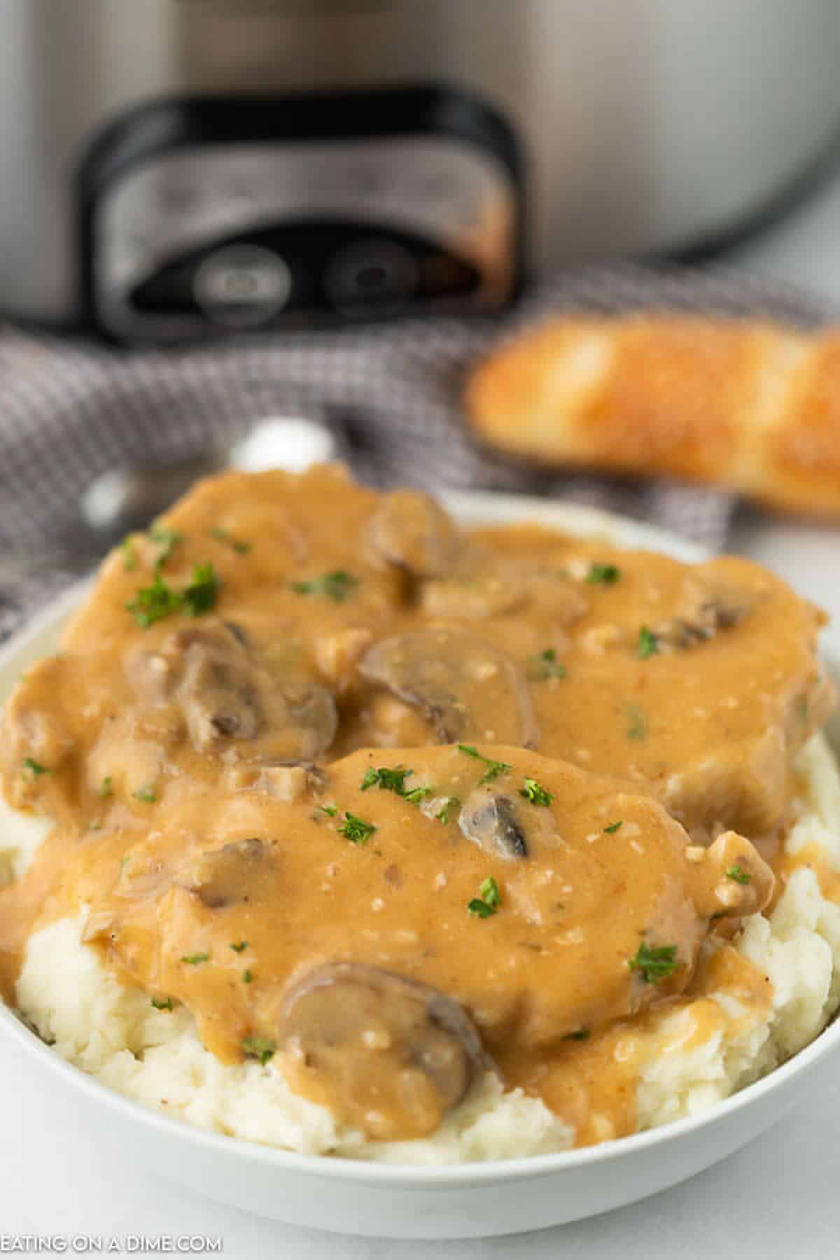 smothered pork chops on mashed potatoes in a white bowl. 