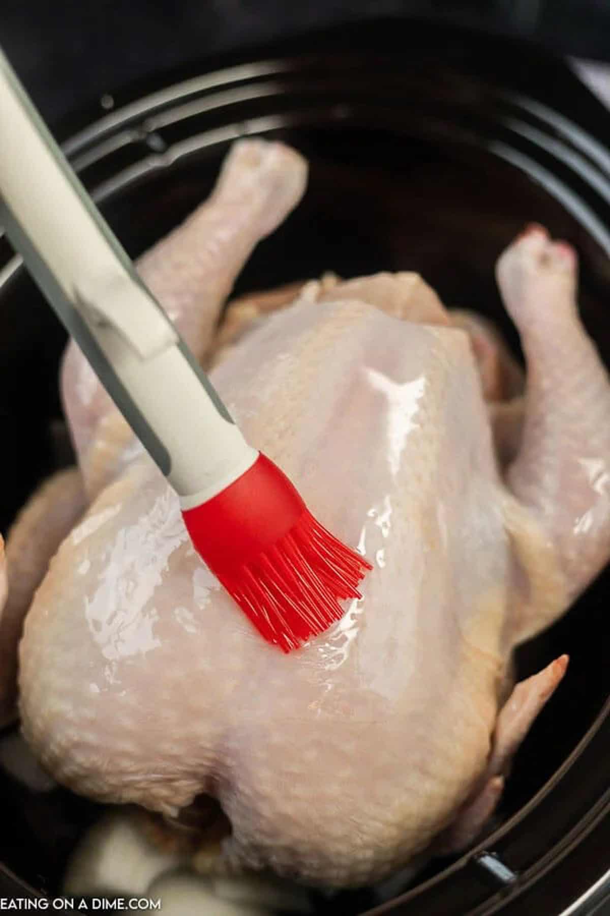 Basting whole chicken with oil with a brush in the slow cooker
