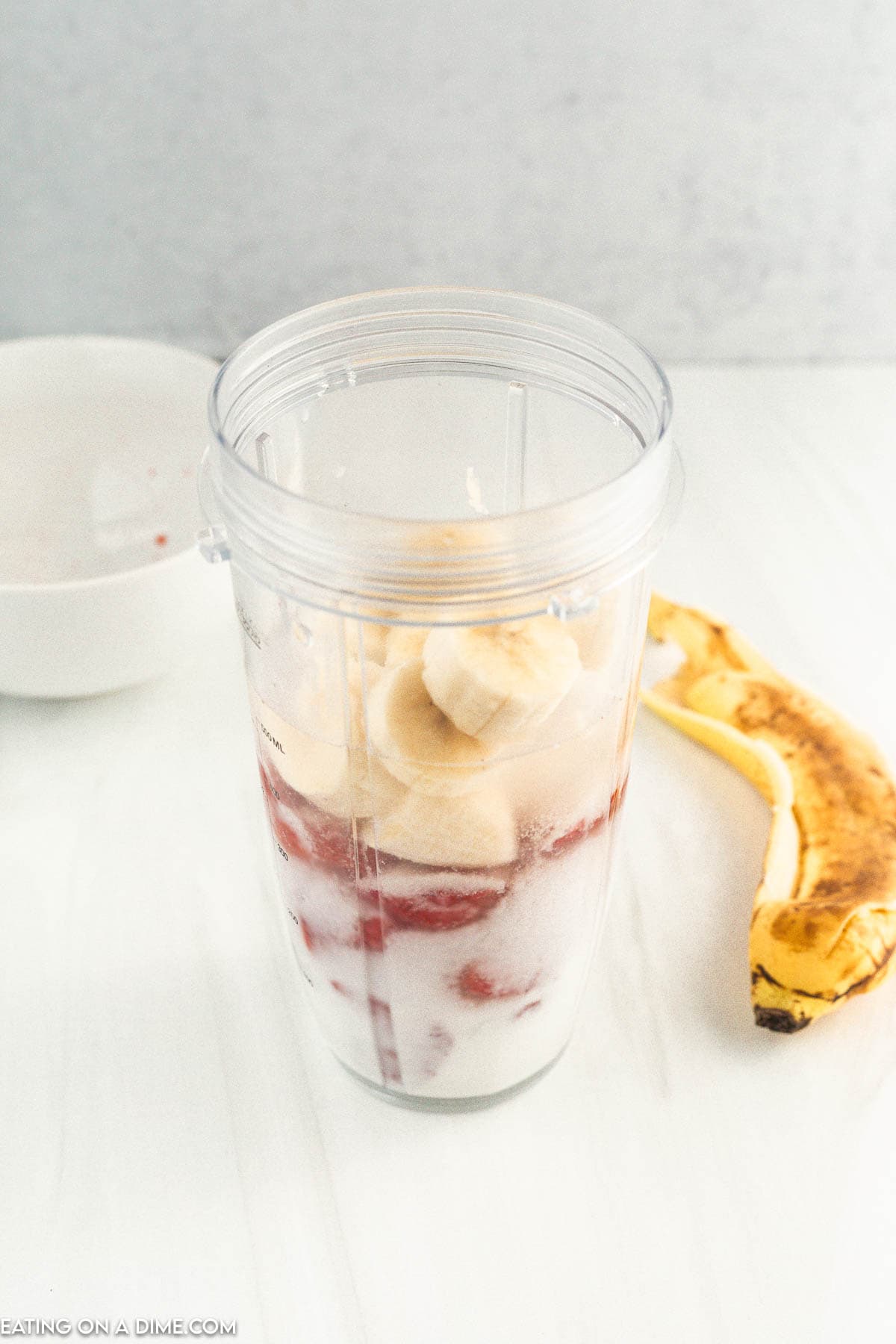 Adding banana and strawberries in a blender cup