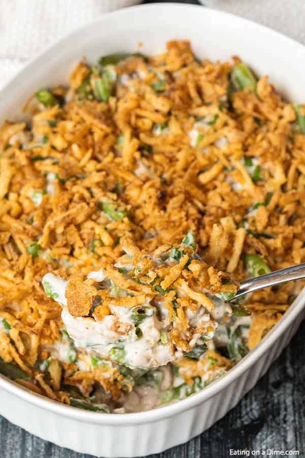 Close up image of green bean casserole with a silver serving spoon. 