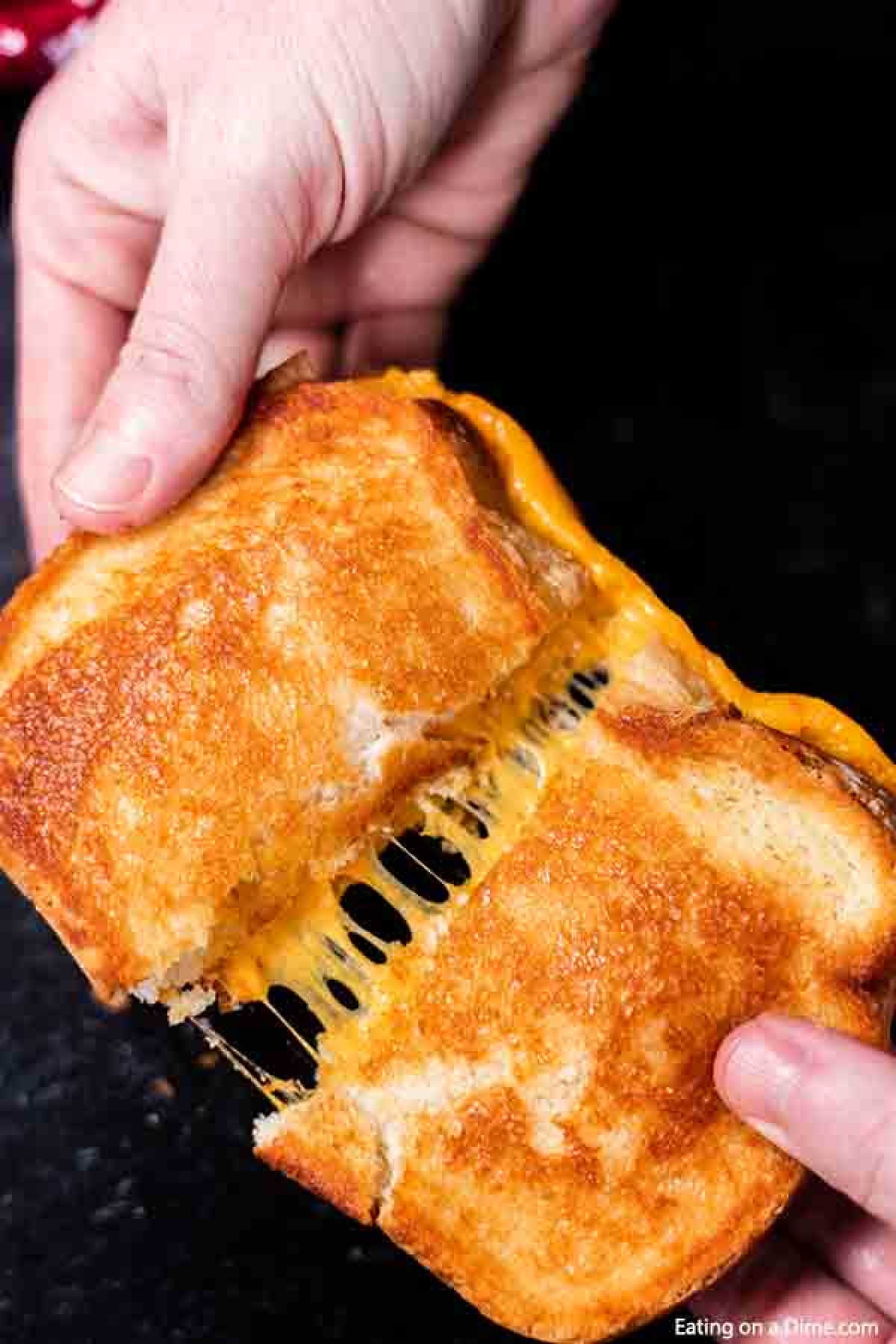 Grilled Cheese Sandwich being pulled apart by hands with the melty cheese in the middle