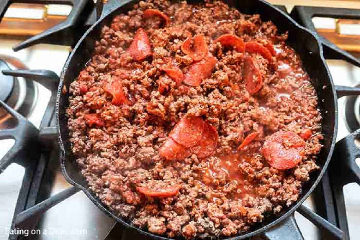 Adding in the sauce and pepperoni to the beef mixture in the skillet