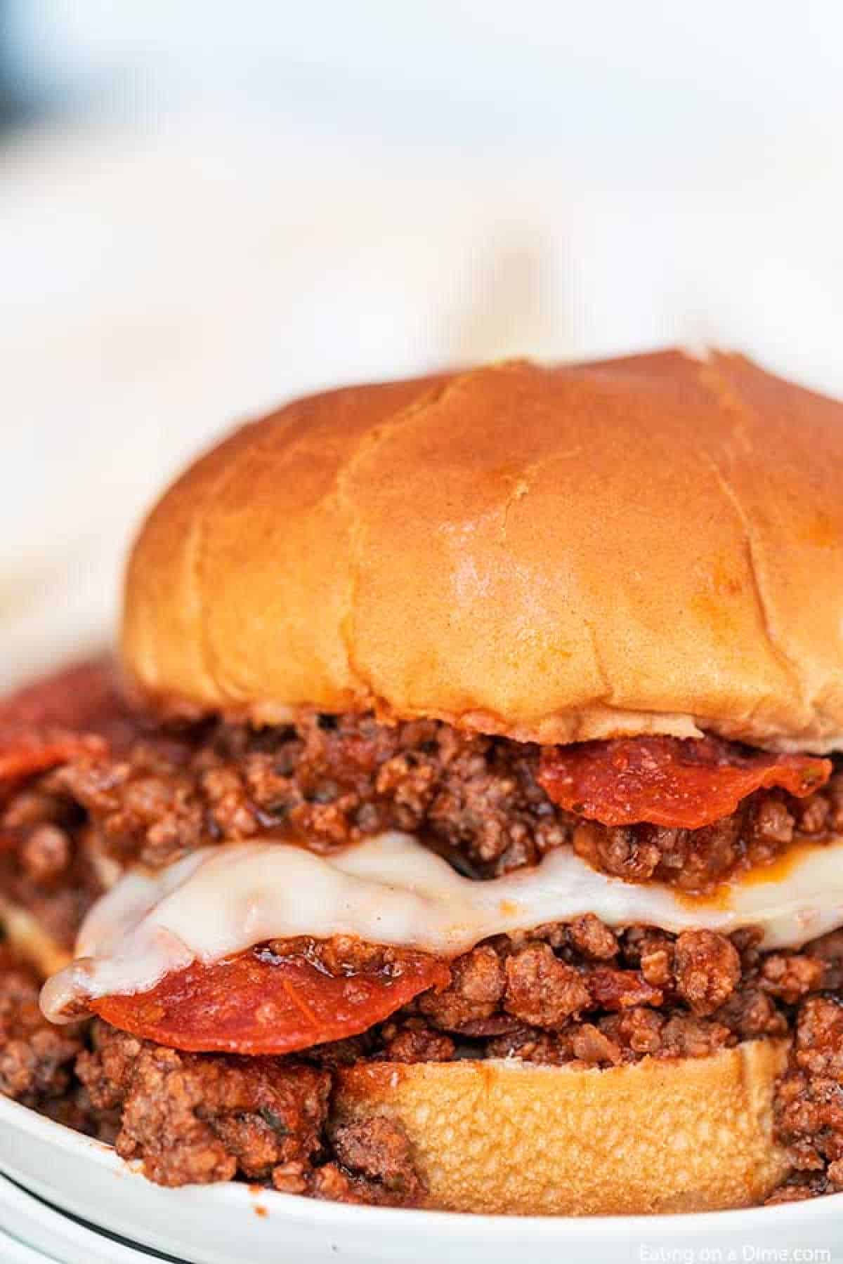 Pepperoni pizza sloppy joes are so fun to eat and easy to make. Everything you love about pizza gets combined with this tasty sloppy joes recipe for a quick meal. Cheesy beef, pepperoni and more make Pizza Sloppy Joes amazing. #eatingonadime #pepperonipizzasloppyjoes Close up image of Pepperoni Pizza Sloppy Joes