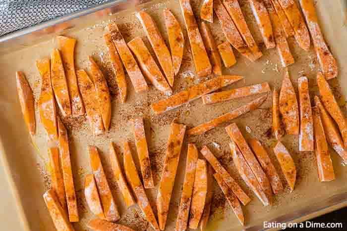 Spreading the seasoned sweet potato on a baking sheet