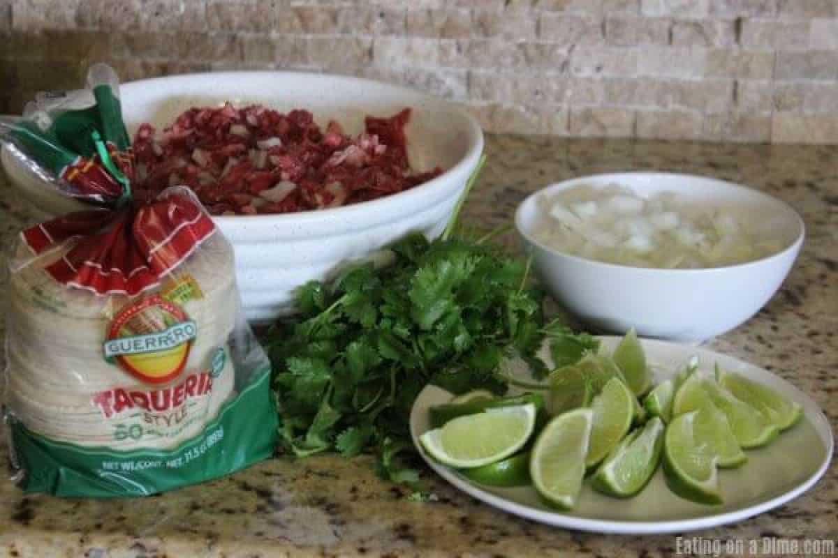 Ingredients needed to make street tacos: steak, tortillas, cilantro, white onions and limes. 