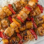 Teriyaki Chicken Skewers with grilled pineapple, red and green bell peppers, sprinkled with sesame seeds, served over a bed of white rice.